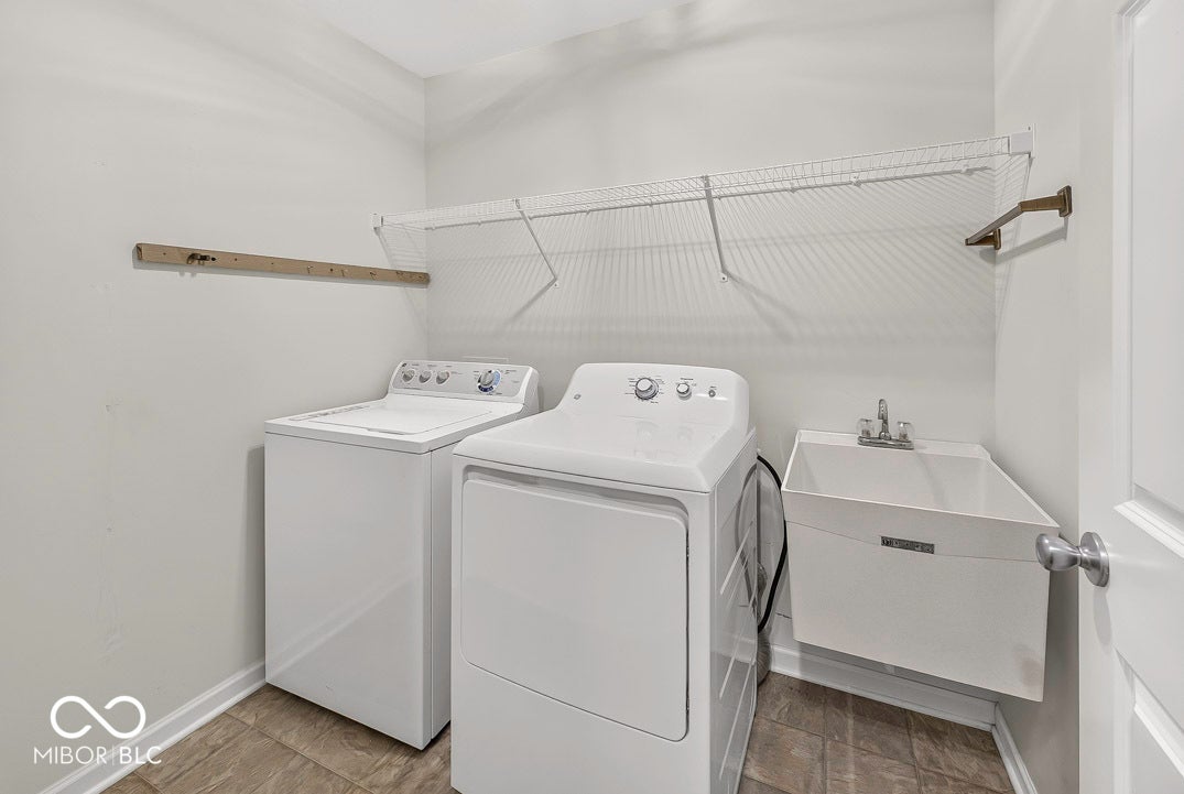 Laundry area featuring a utility sink, wire shelving, and wood-finish flooring