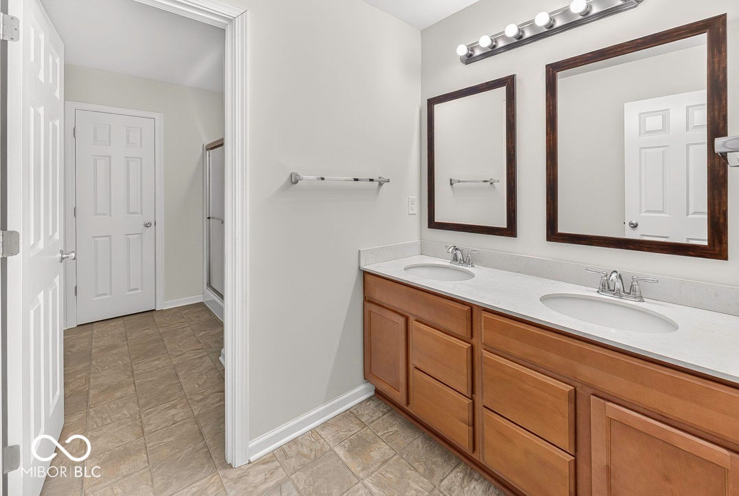 Double vanity with dual undermount sinks, wood-finish cabinetry, and framed mirrors