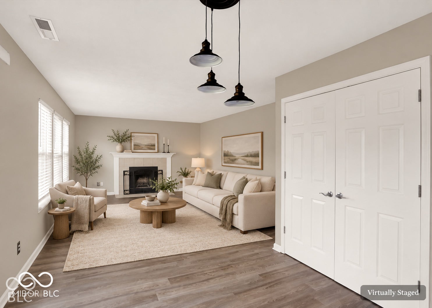 Wood-finish flooring, three-light pendant fixture, fireplace with mantel, white interior trim, and panel-style doors
