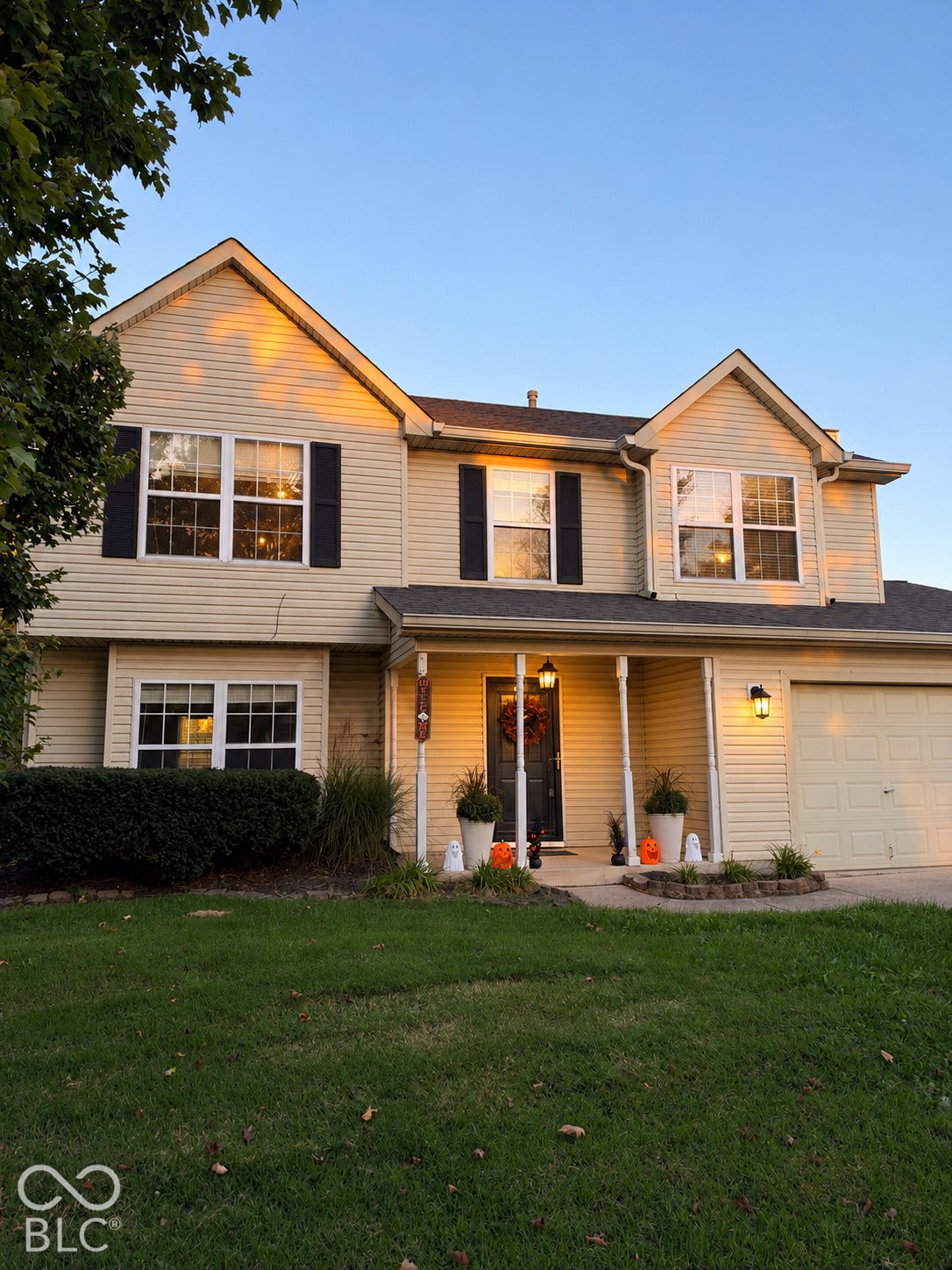 Two-story residence featuring siding exterior, an attached garage, a covered front porch, and a manicured lawn