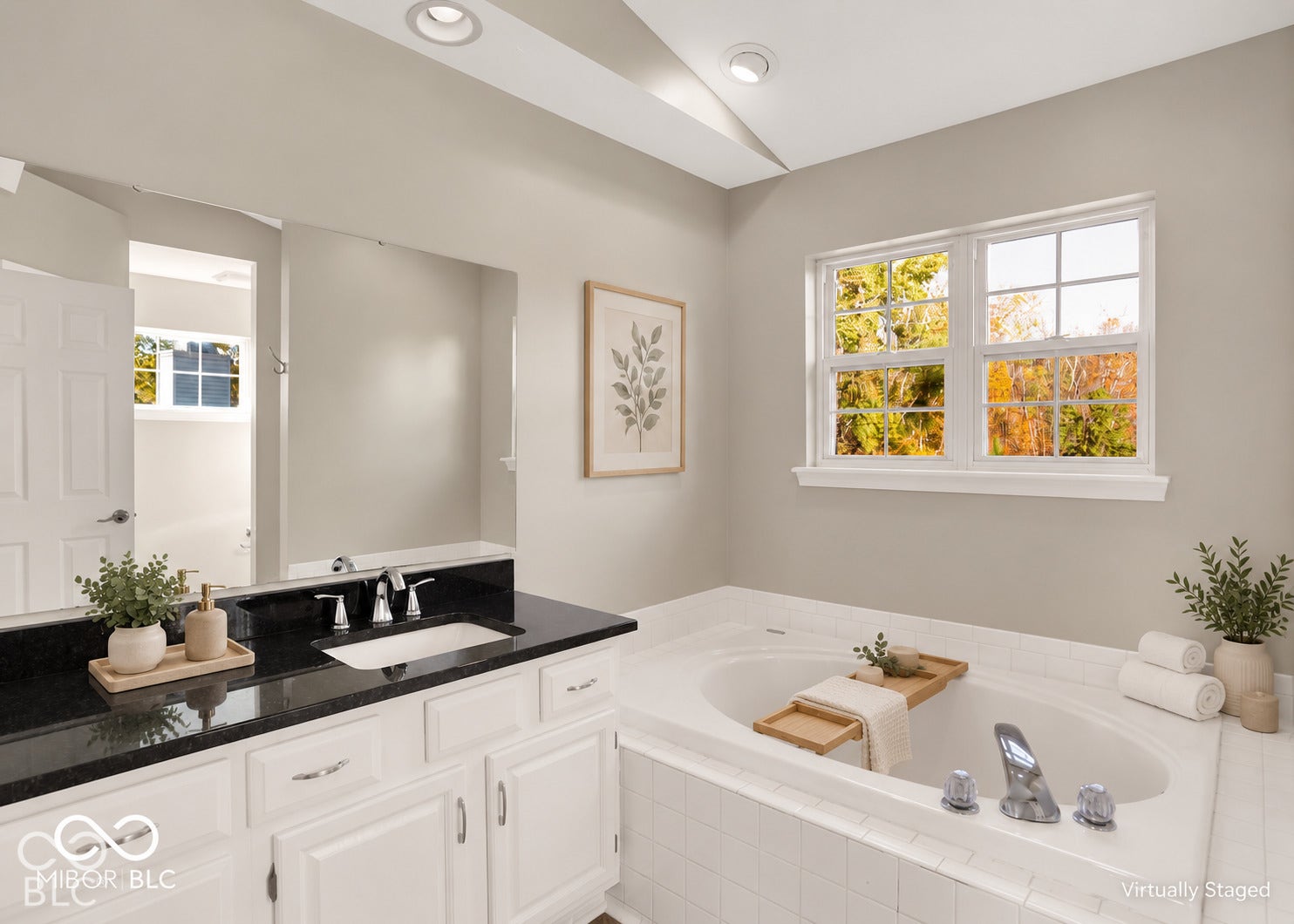 Recessed lighting illuminates a built-in soaking tub with chrome fixtures