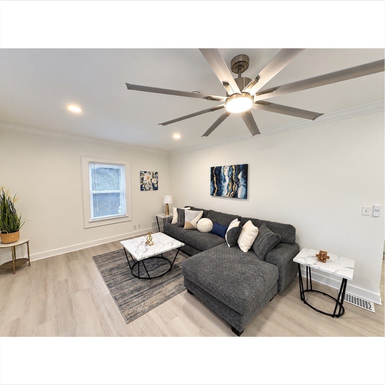Wood-finish flooring, recessed lighting, crown molding, a ceiling fan with integrated lighting, and a double-pane window