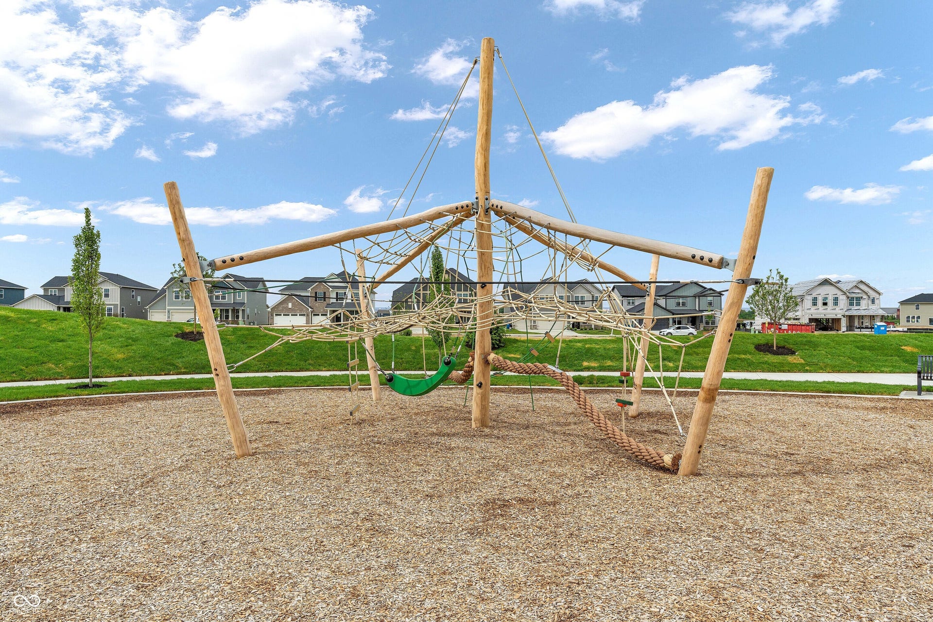 Community playground featuring a rope climbing structure and wood chip surfacing
