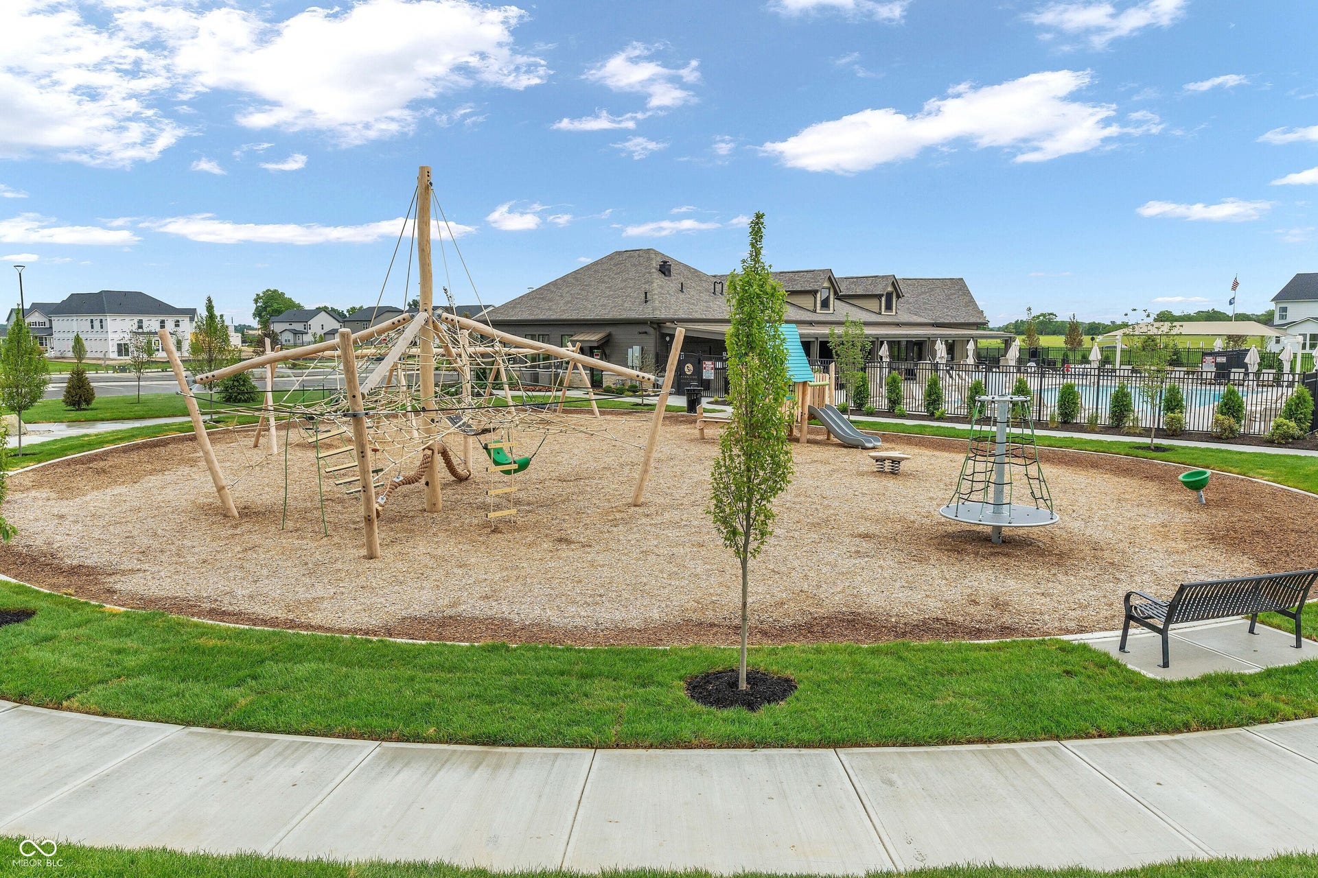 Outdoor play area featuring a large climbing structure, slide, and merry-go-round