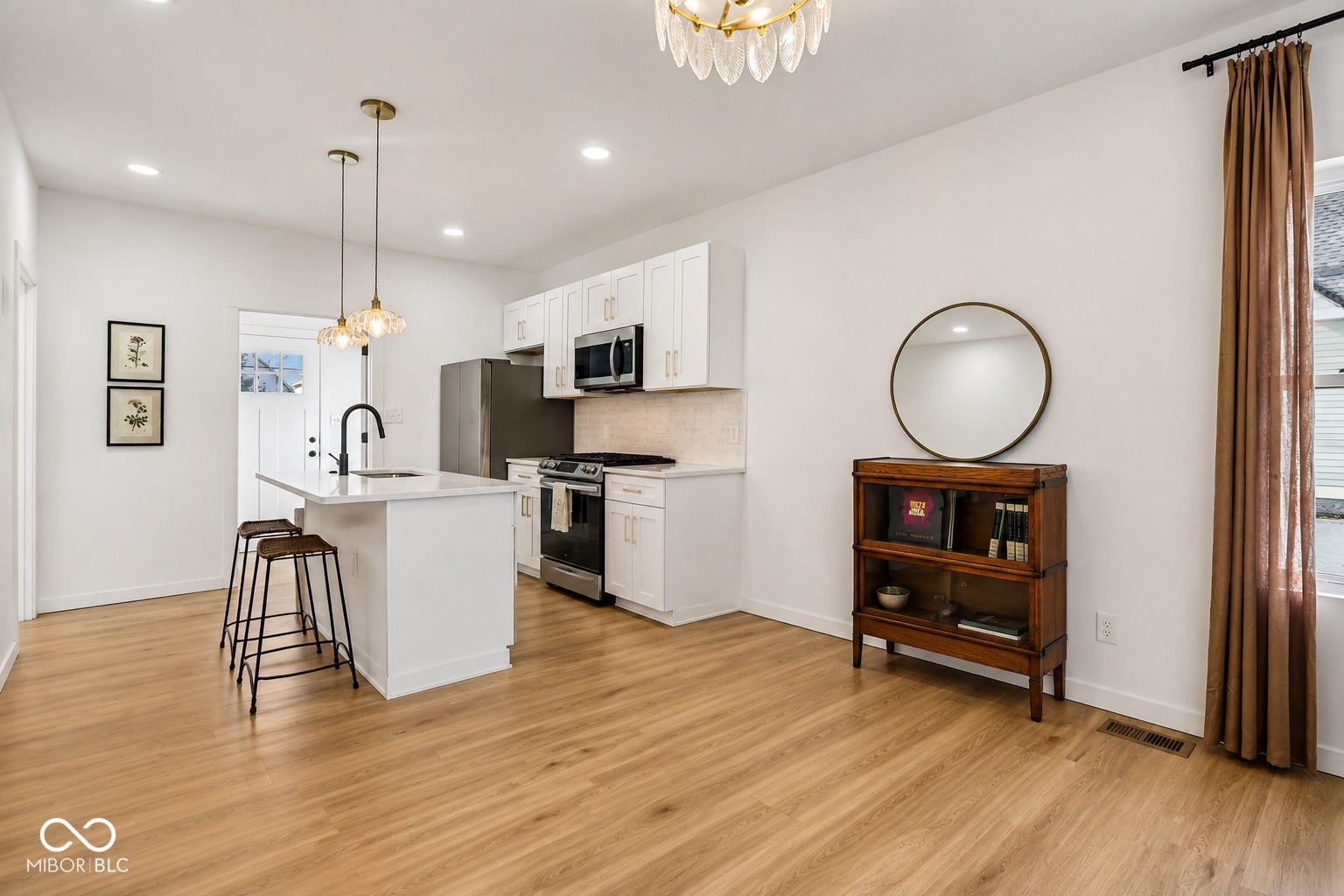 Open-concept living space with wood-finish flooring, recessed lighting, and a modern kitchen island featuring a sink