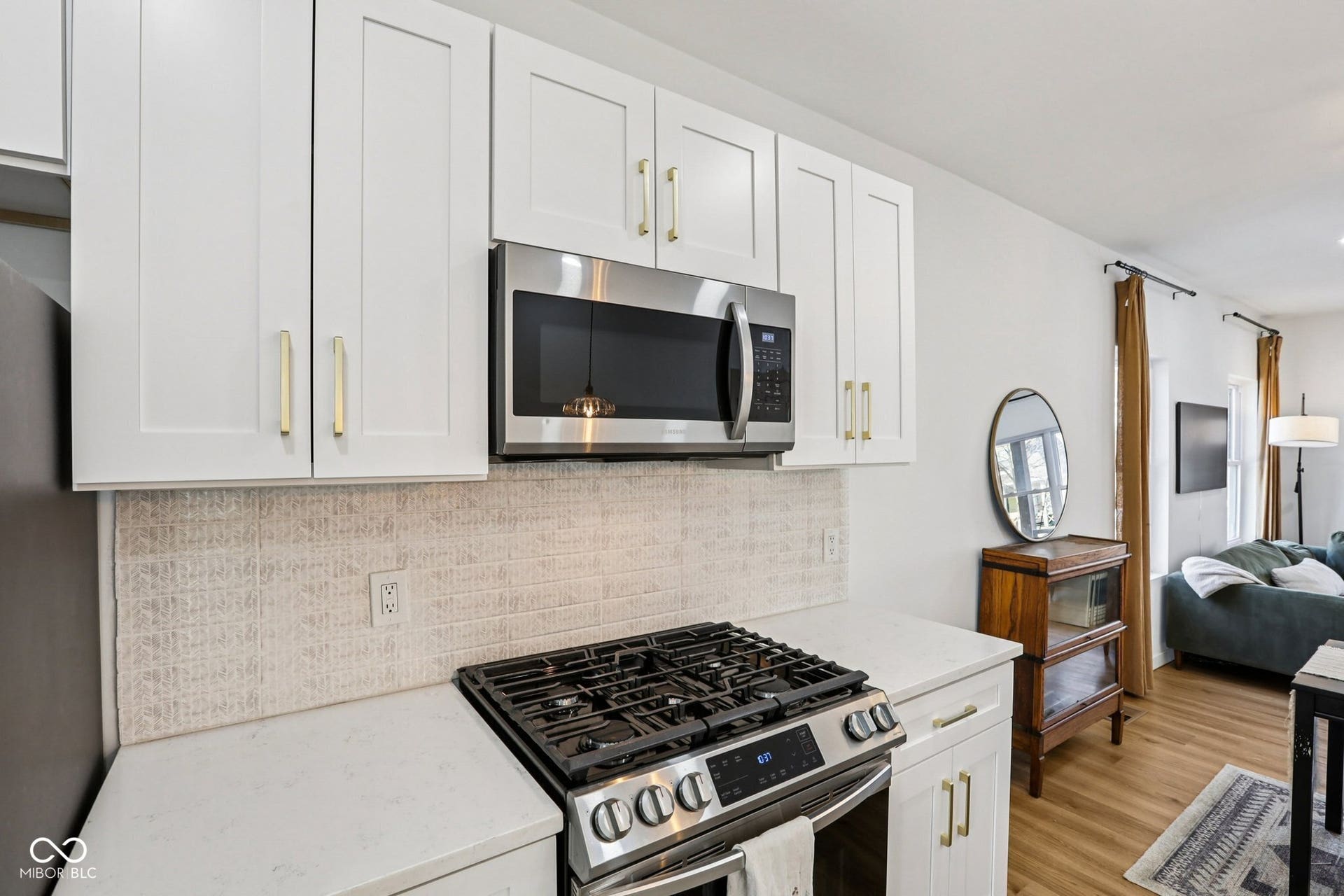 Modern kitchen featuring white shaker cabinetry, stainless steel microwave, and gas range