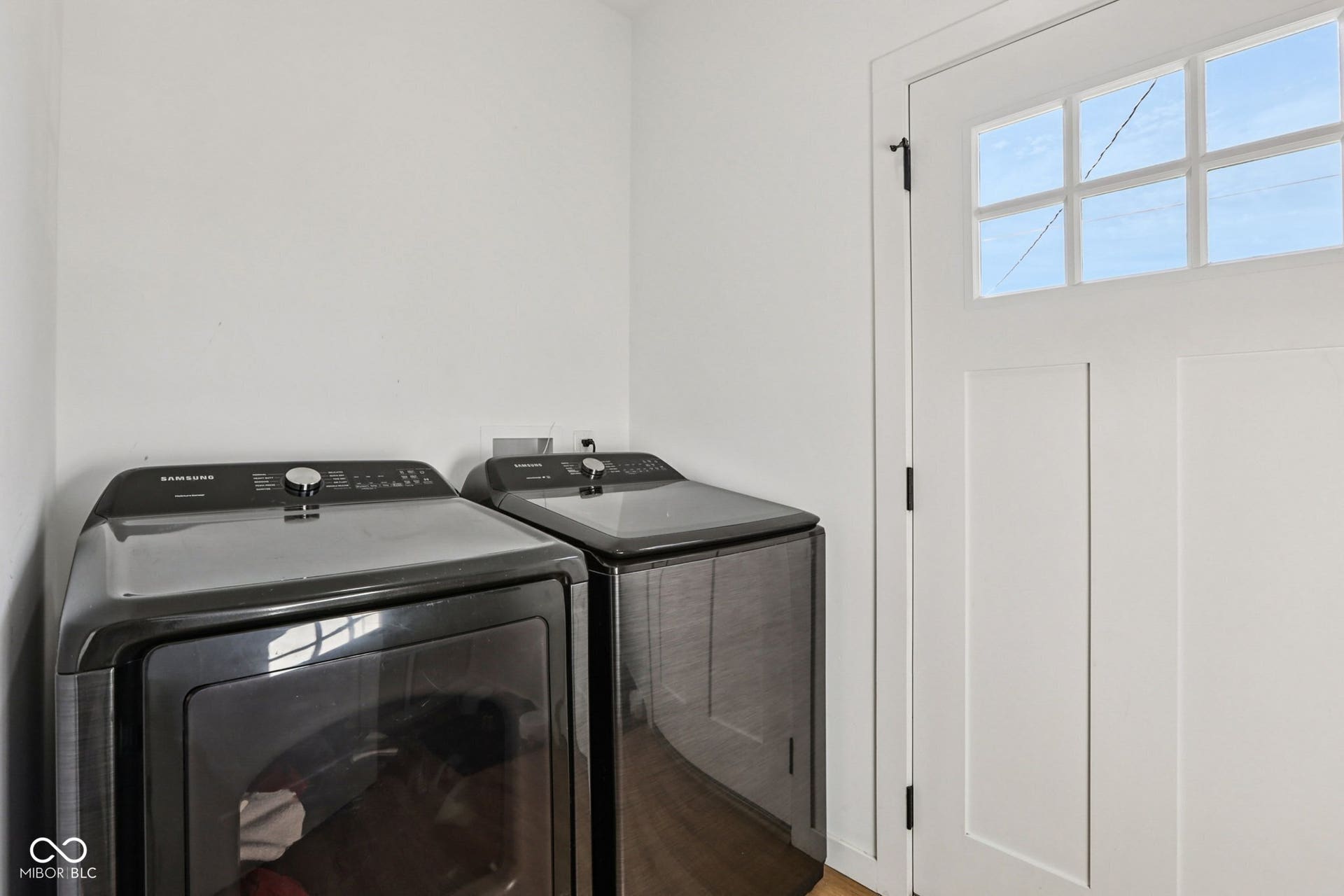 Dedicated laundry area featuring a white paneled door with six-light window panes on the main floor