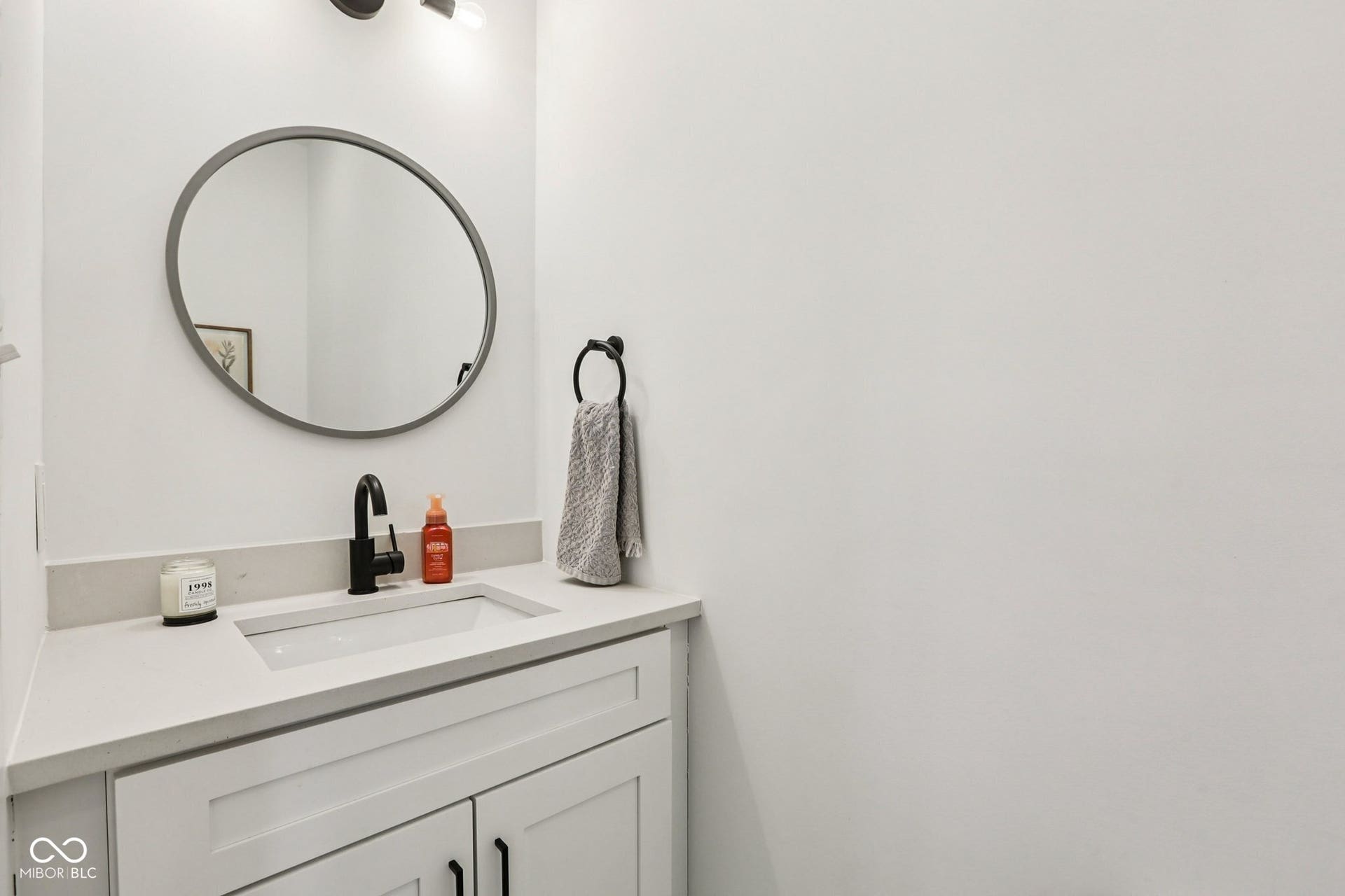 Modern vanity featuring a rectangular undermount sink, light-toned countertop, and matte black faucet