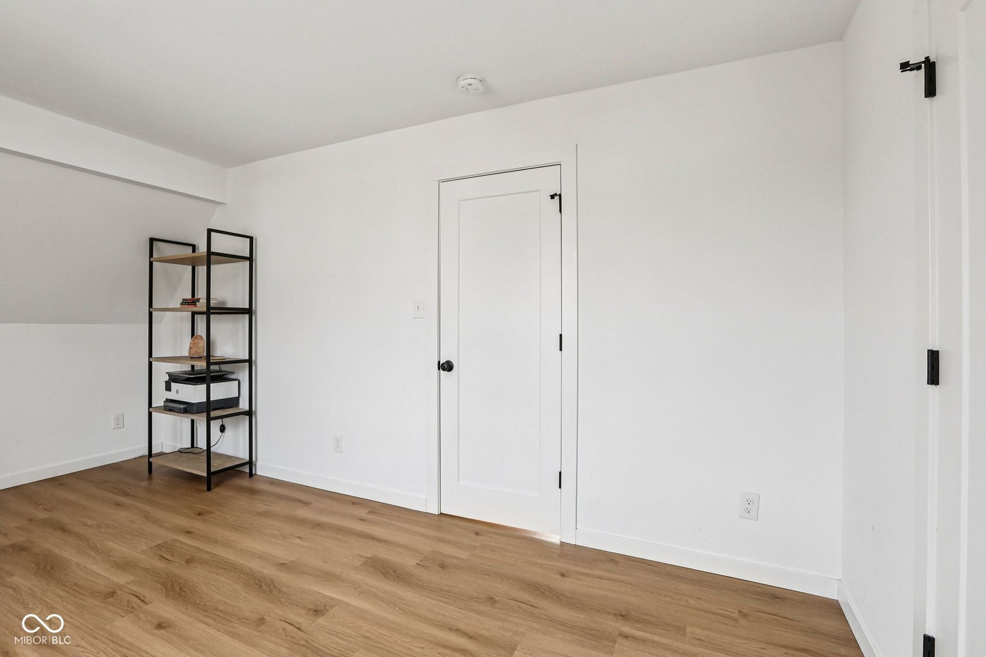 Bedroom 3: featuring wood-finish flooring, white walls, and a crisp white door with black hardware