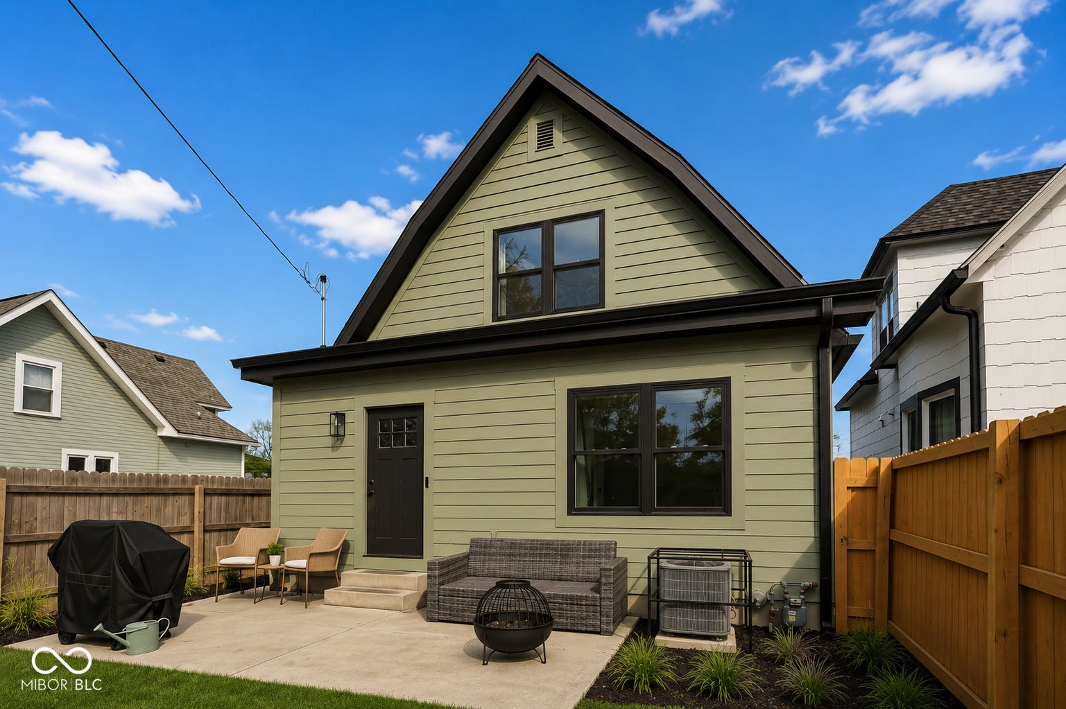 Virtually Altered - Rear exterior featuring light green siding with dark trim, black-framed windows, and a black paneled door
