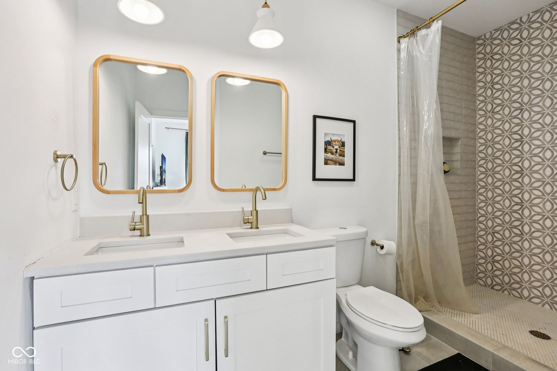 Bathroom featuring a dual vanity with white cabinetry, gold-finish hardware, and a light-toned countertop