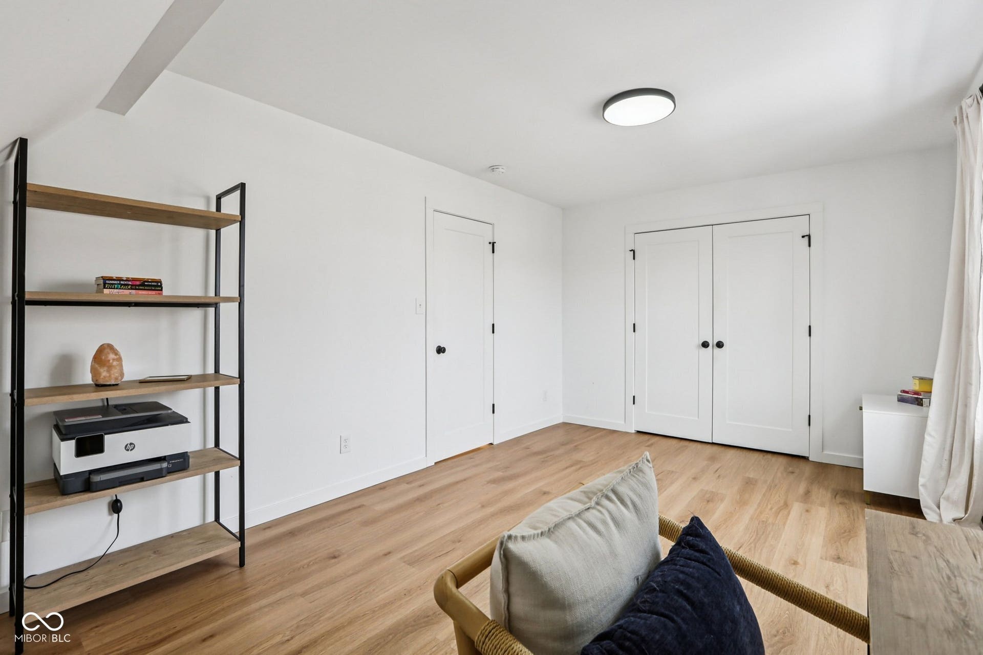 bedroom 3: Light wood-finish flooring with white walls and trim, featuring a flush-mount ceiling light