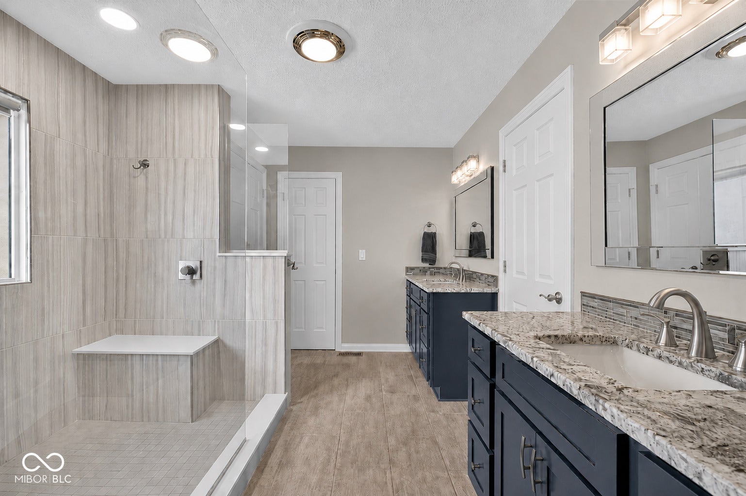 Walk-in shower with a built-in bench, glass enclosure, and separate vanities
