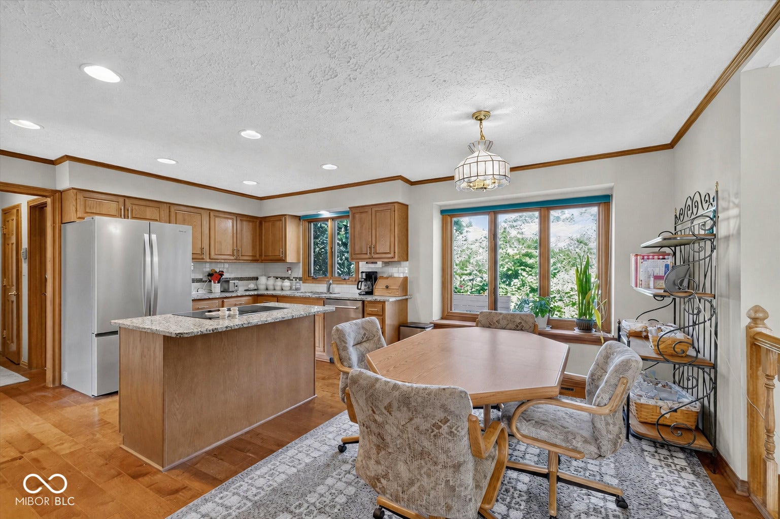 Kitchen featuring wood-finish flooring, recessed lighting, wood cabinetry, stainless steel appliances, and a central island with a stone countertop