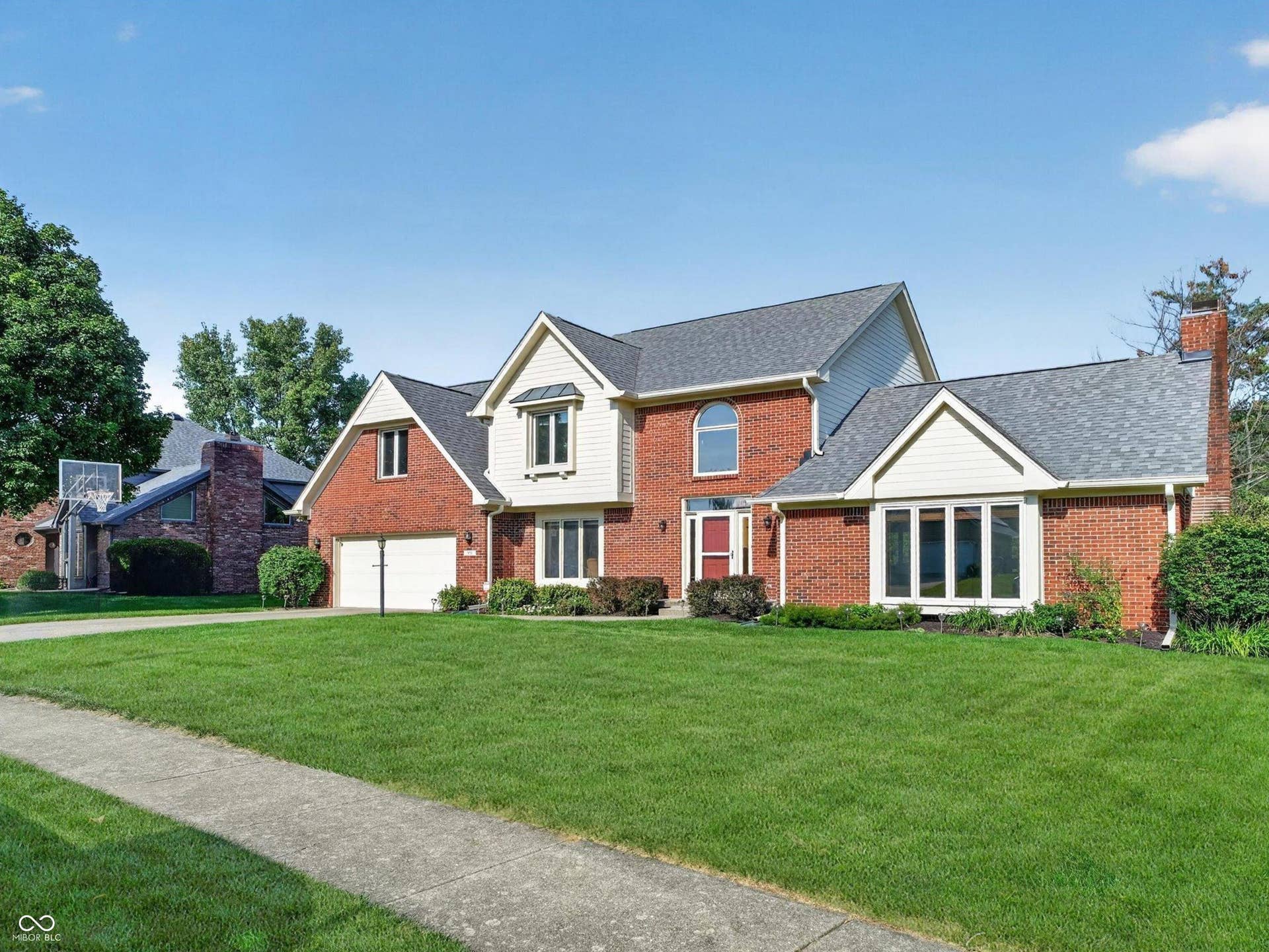 Traditional brick exterior featuring a multi-gabled roofline, a two-car garage, and a bay window