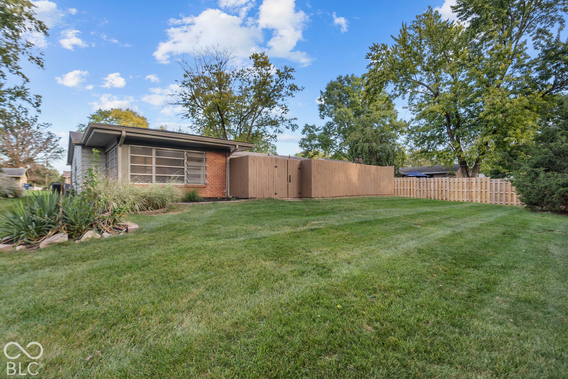 Expansive lawn area, wood privacy fencing, decorative landscaping