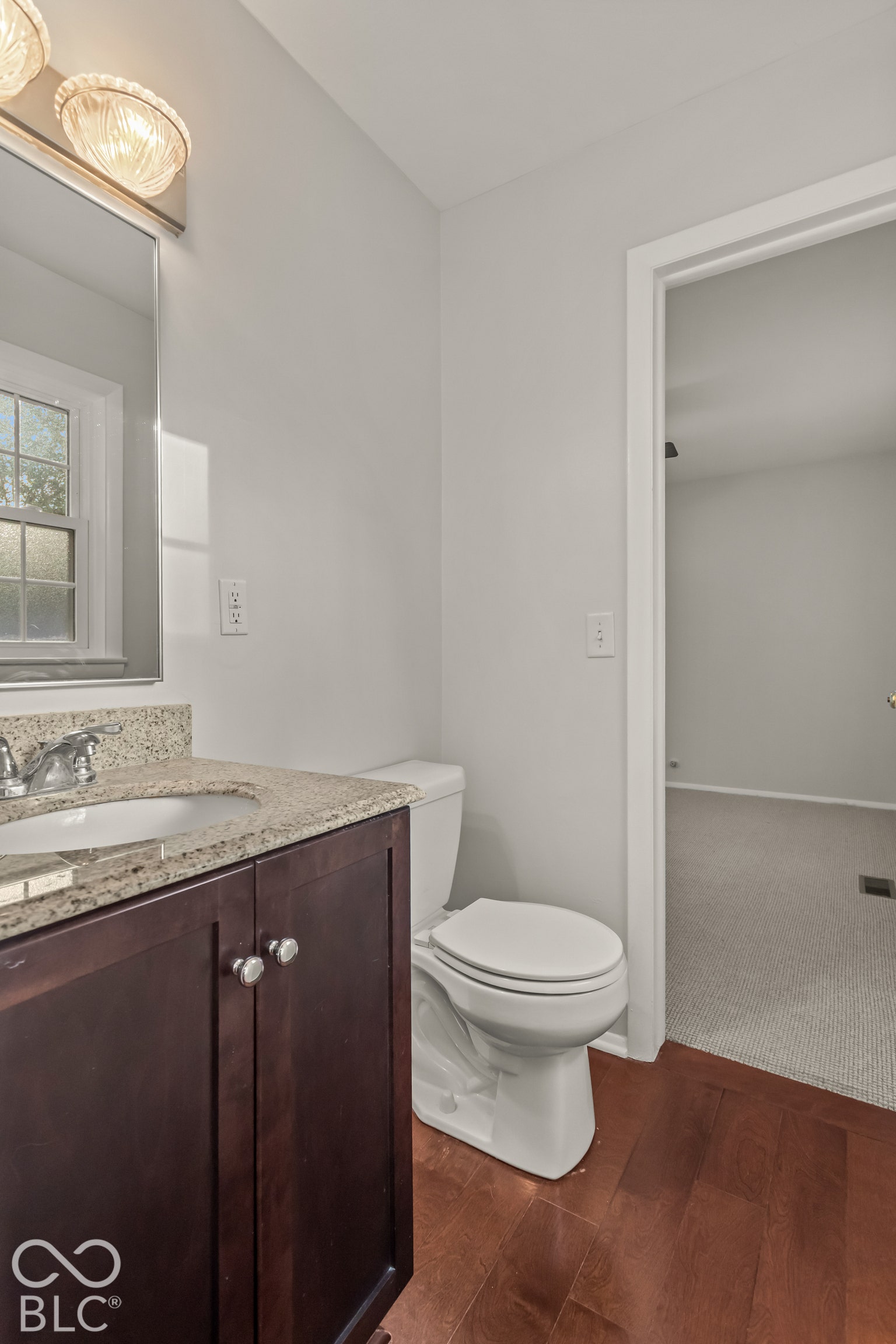 Dark wood-finish vanity with a stone-finish countertop, undermount sink, and polished chrome faucet