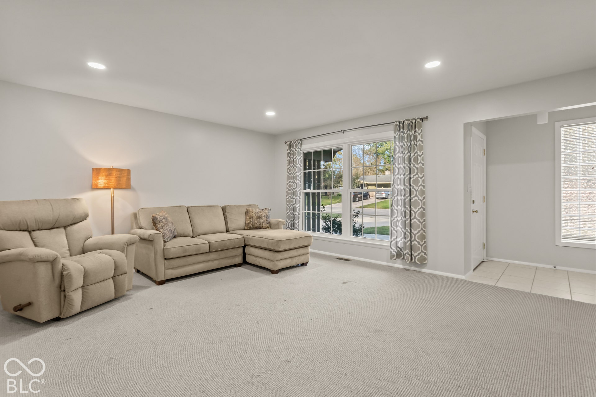 Recessed ceiling lighting, large window with natural light, wall-to-wall carpeting, tiled entryway, and glass block window