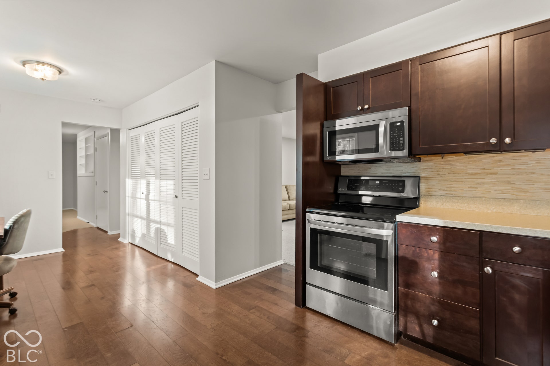Kitchen with wood-finish flooring, dark wood cabinetry, stainless steel microwave, and a stainless steel range