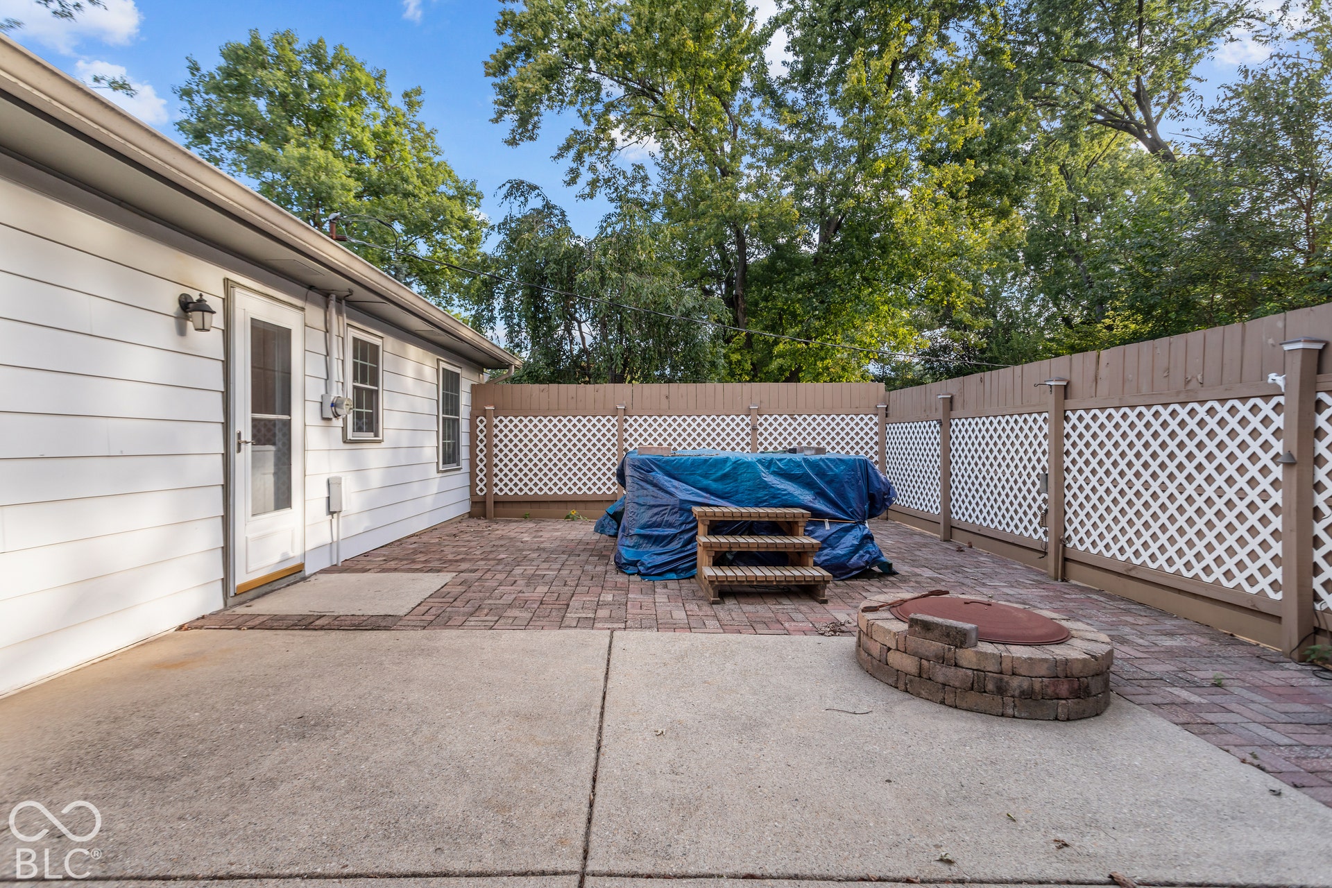 Spacious patio featuring a concrete slab, a brick paver section, and a hot tub