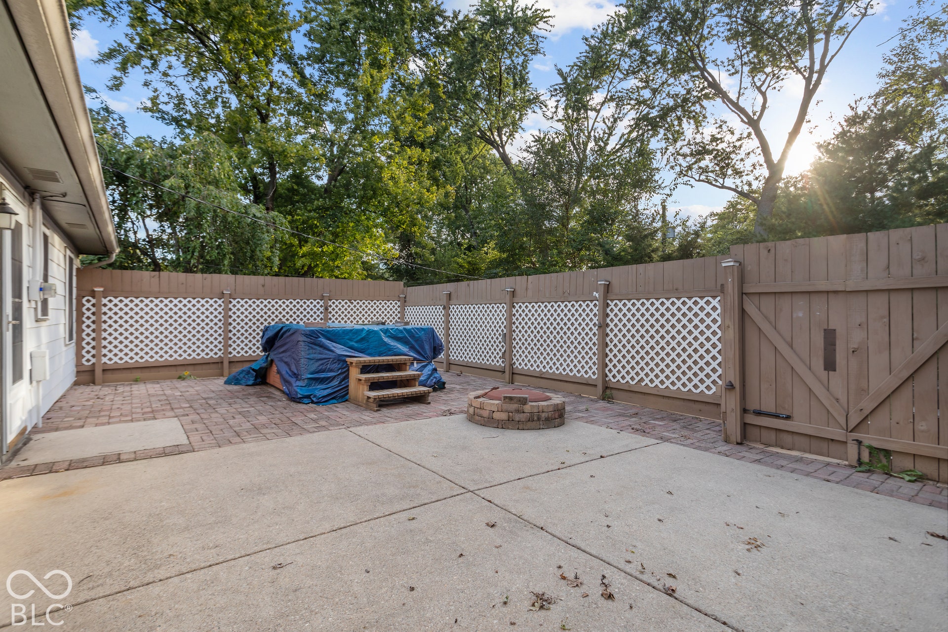 Private patio with a Hot Tub, wood privacy fence, and concrete slab flooring