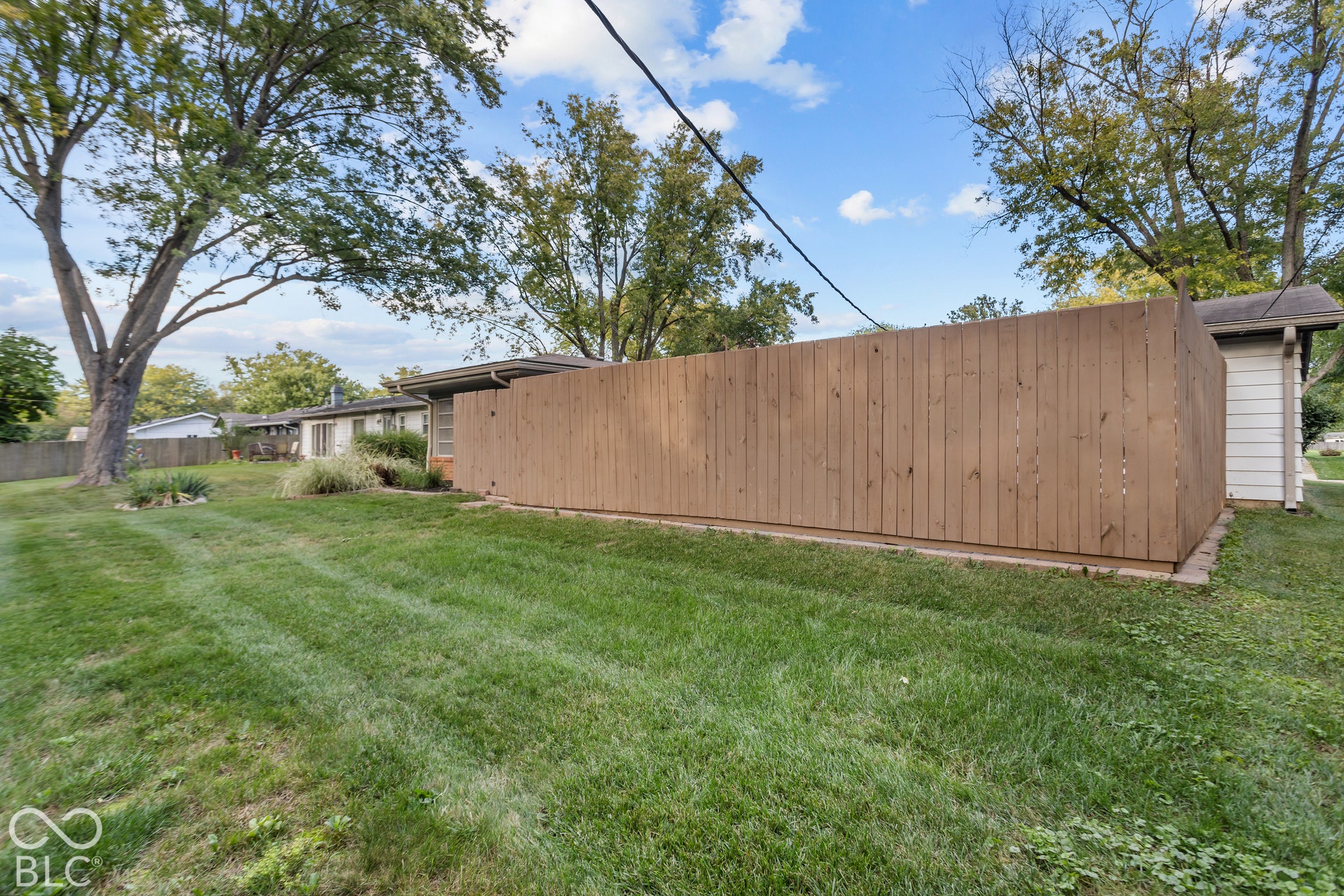 Spacious yard featuring a privacy fence, mature trees, and landscaping