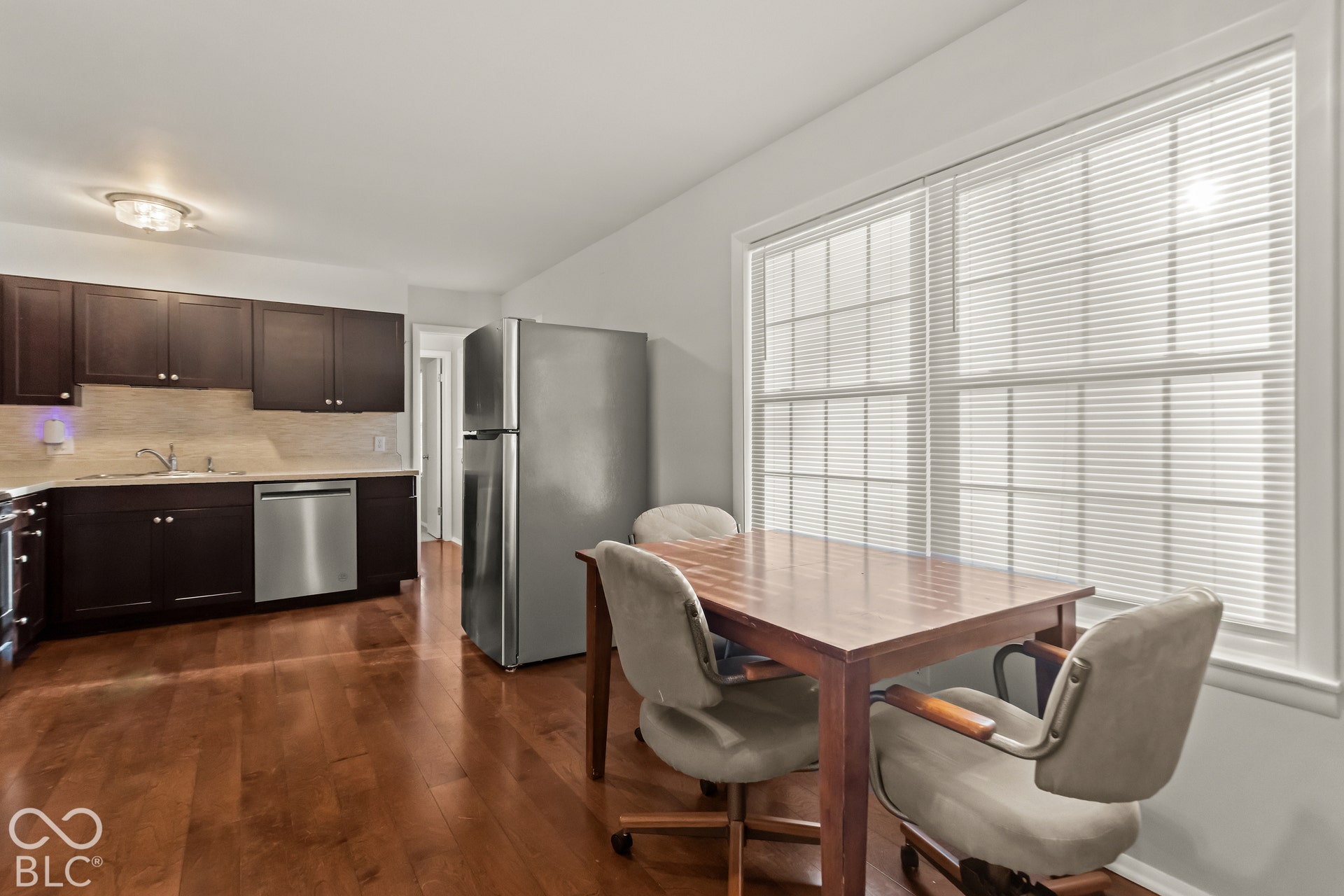 Kitchen featuring wood-finish flooring, dark wood cabinetry, a tile backsplash, and stainless steel appliances
