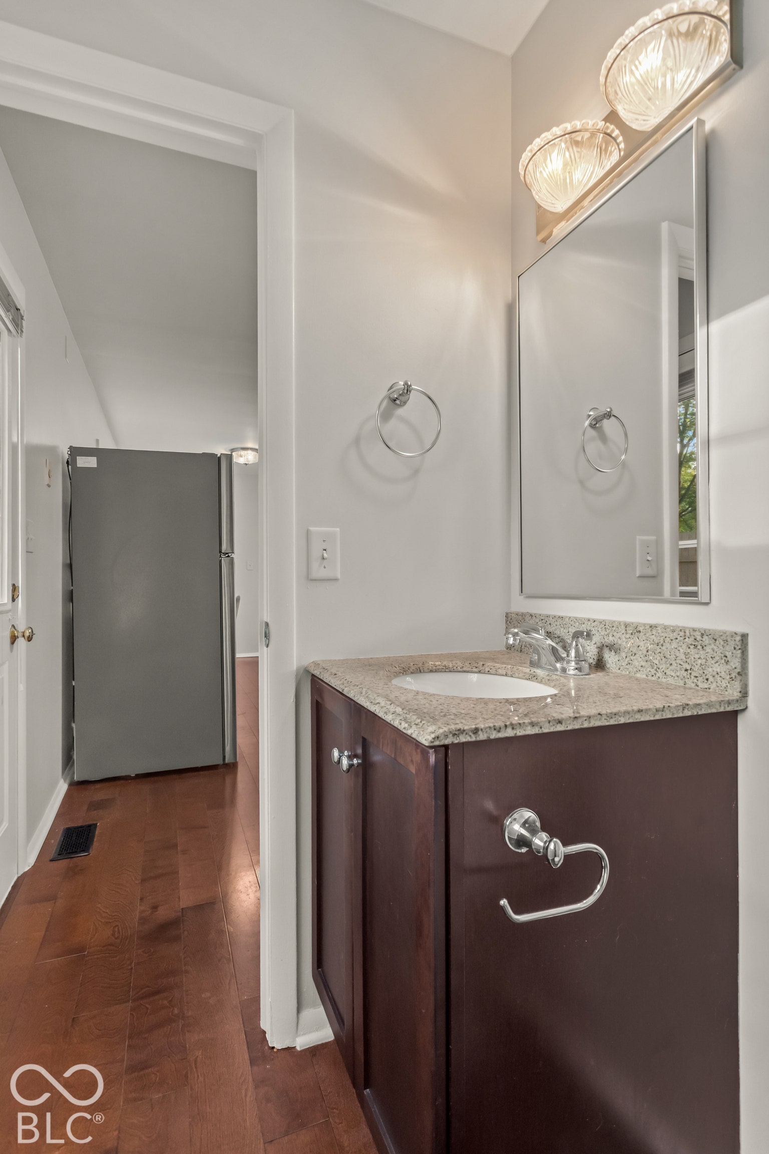 Granite countertop vanity with an undermount sink, wood-finish cabinetry, and chrome fixtures