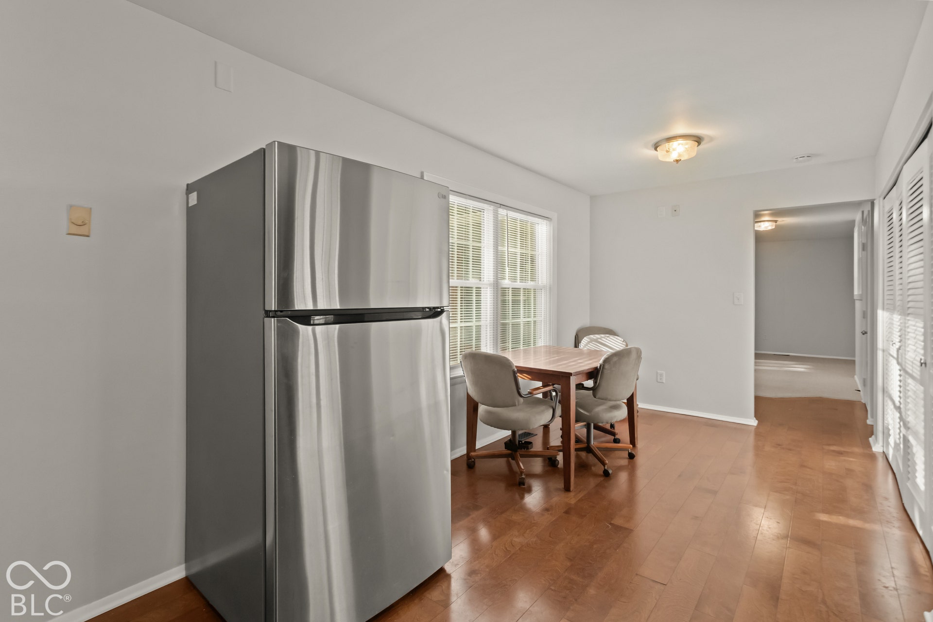 Recessed window with white trim, wood-finish flooring, overhead flush-mount lighting, and bi-fold louvered doors