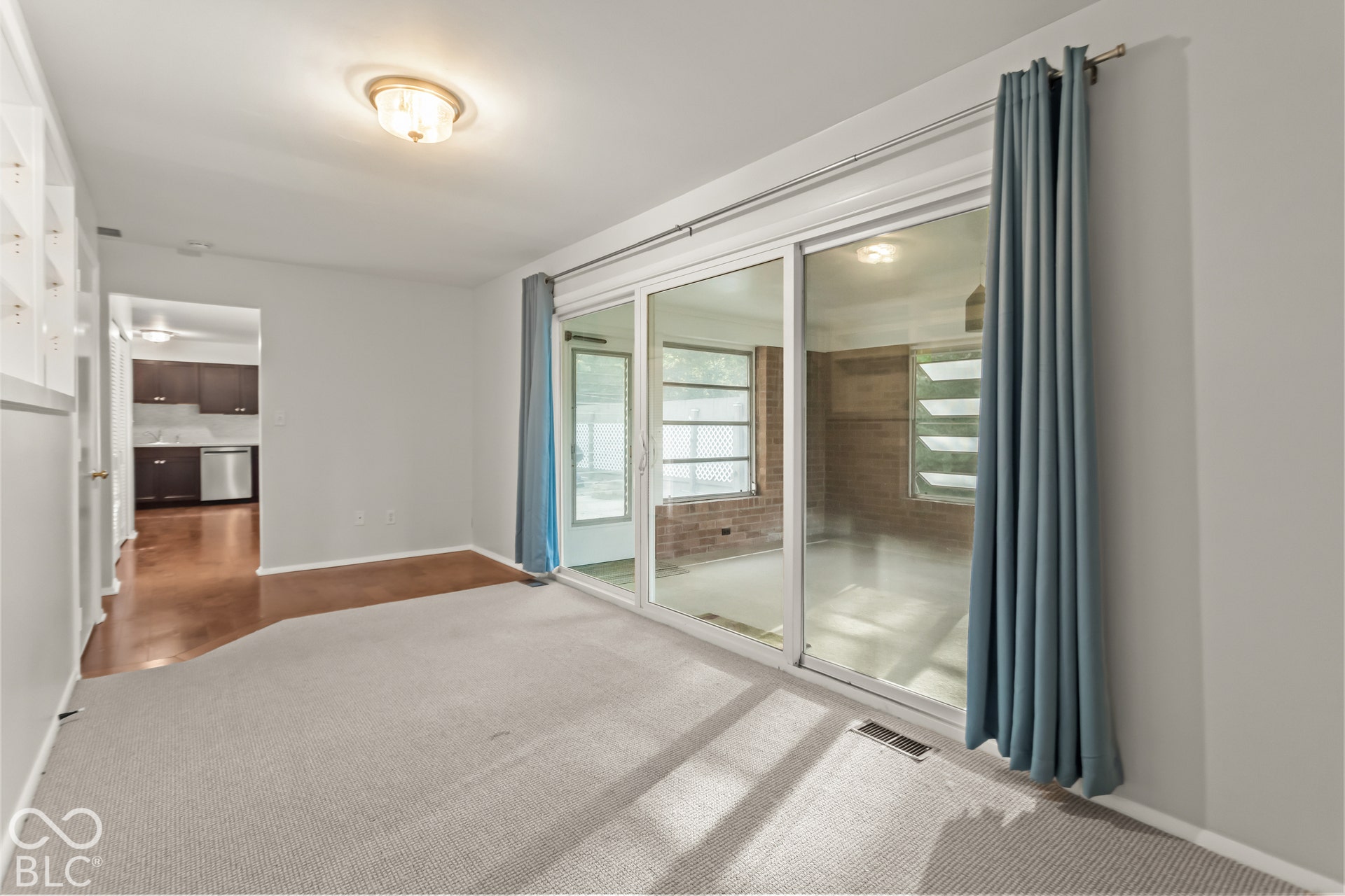 Sliding glass doors, recessed lighting, built-in shelving, carpet flooring, and a ceiling-mounted light fixture