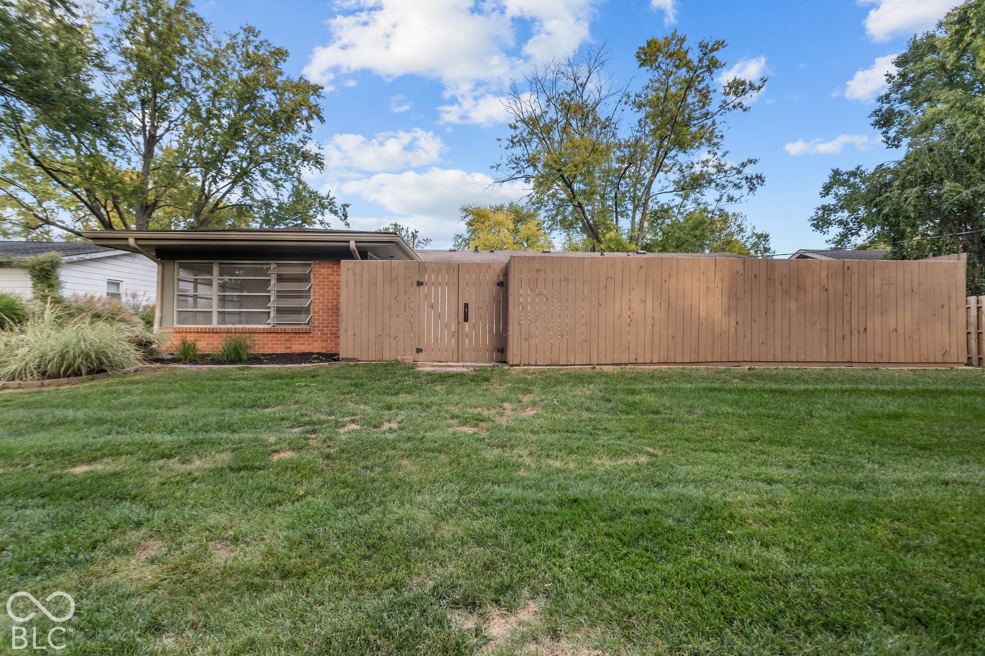 Expansive green lawn, wood privacy fencing, brick exterior