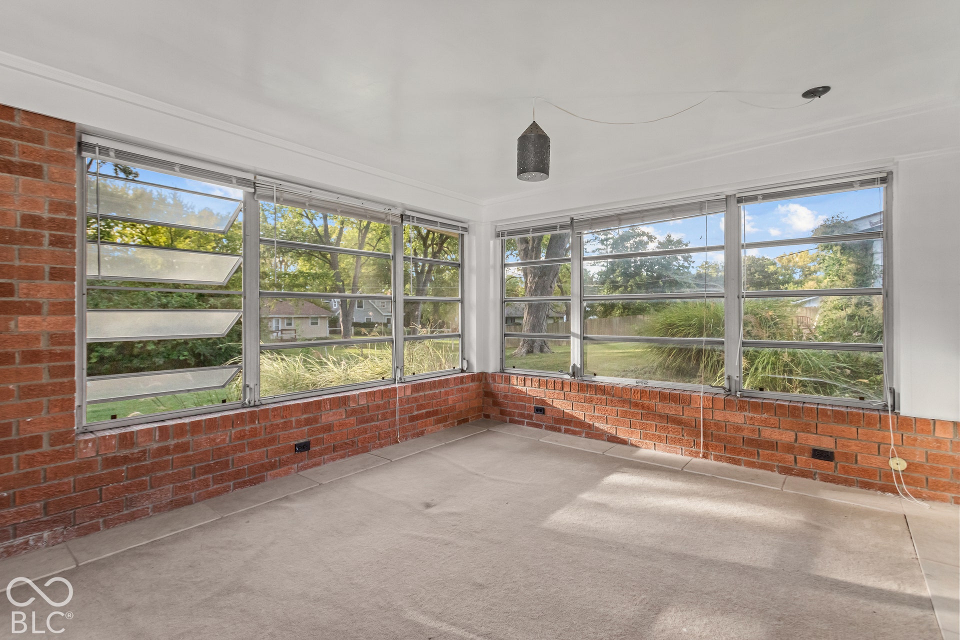 Exposed brick wall accents, large louvered windows, expansive window banks, and a suspended ceiling fixture