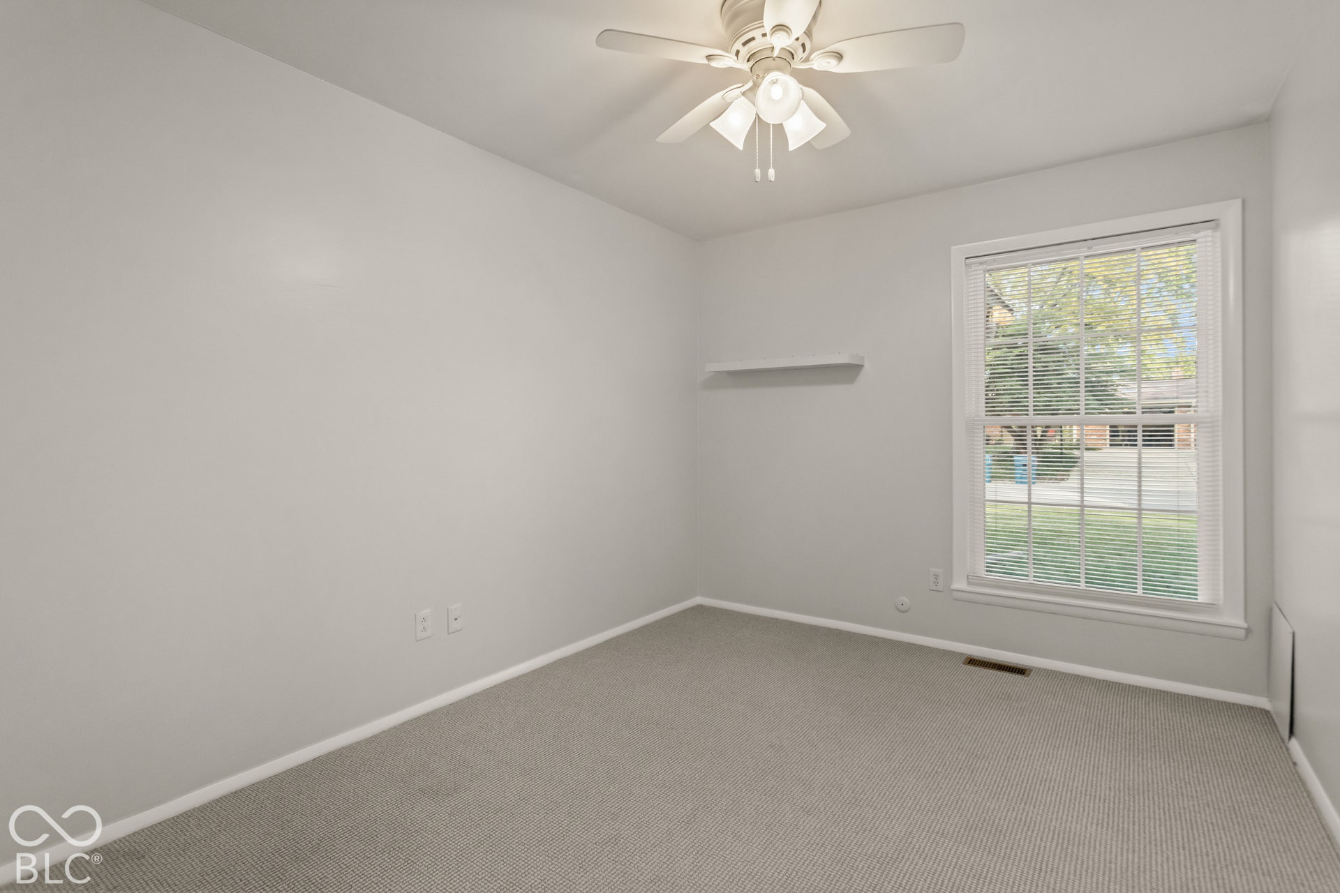 Recessed carpet flooring with white trim, a single window with blinds, and a ceiling fan with integrated lighting