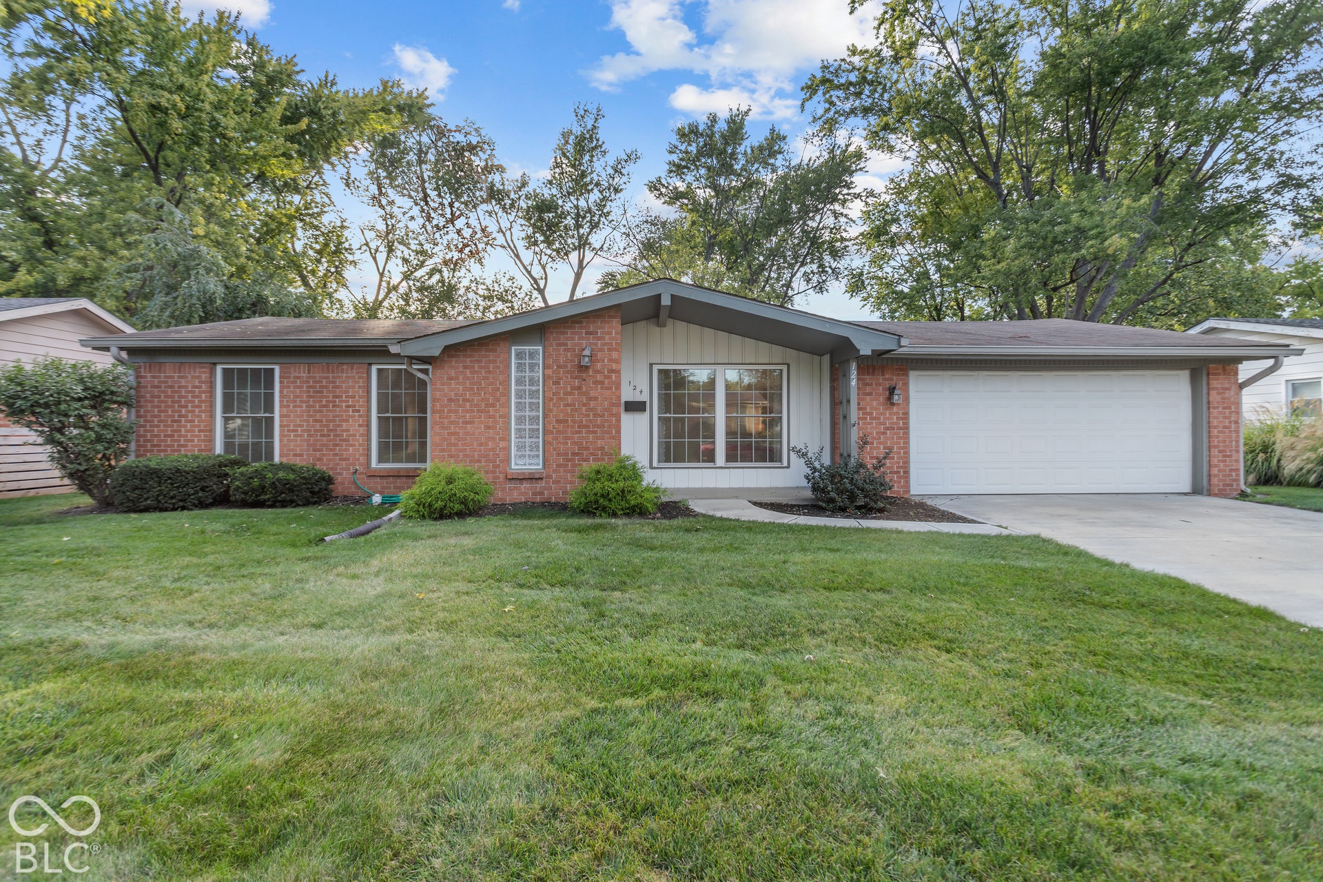 Brick exterior with a white garage door, concrete driveway, and front lawn