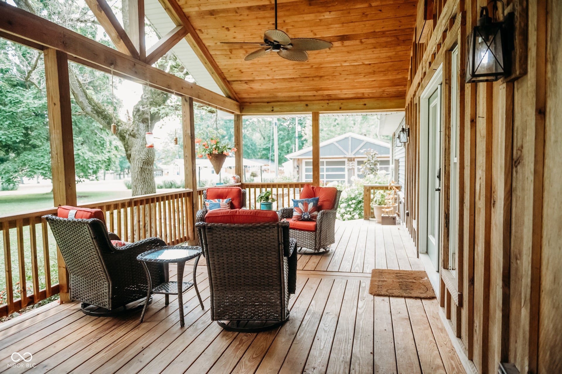 Expansive wood-finish porch featuring a gabled wood-plank ceiling, exposed wood beams, and a ceiling fan
