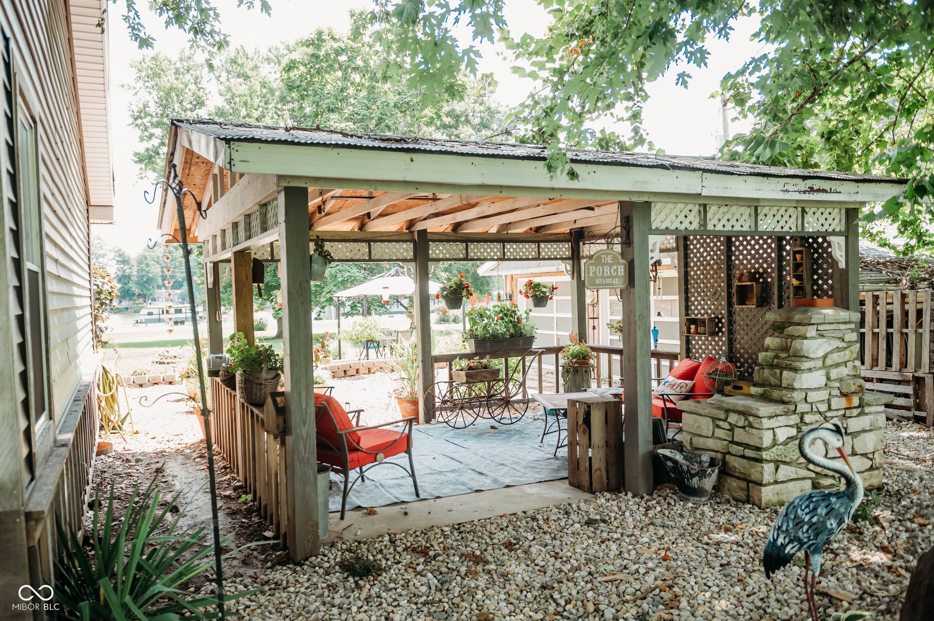 Covered patio featuring a corrugated metal roof, lattice paneling, and a stone-clad outdoor fireplace