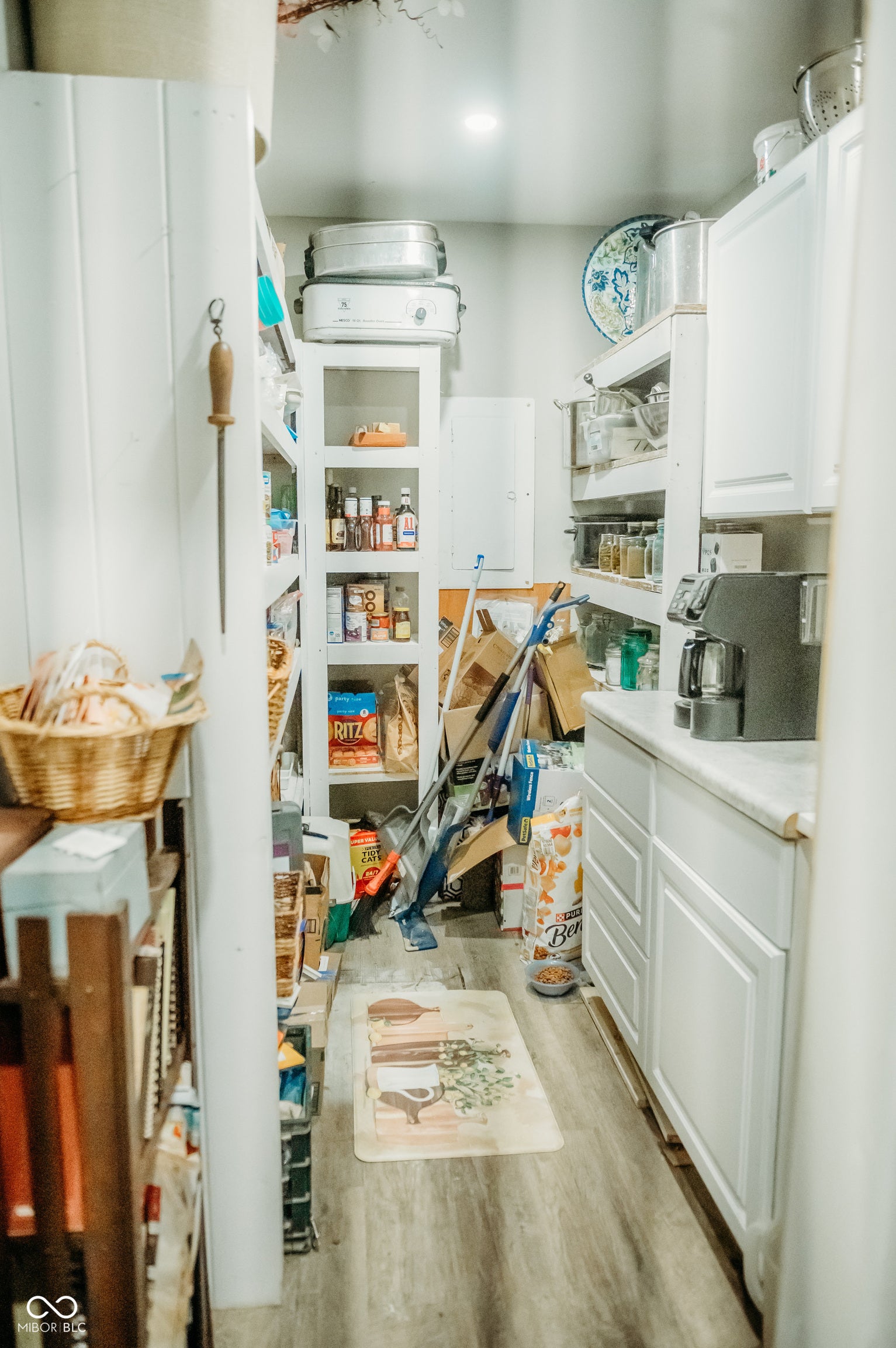 Spacious pantry featuring extensive white cabinetry, open shelving, wood-finish flooring, and a stone-finish countertop
