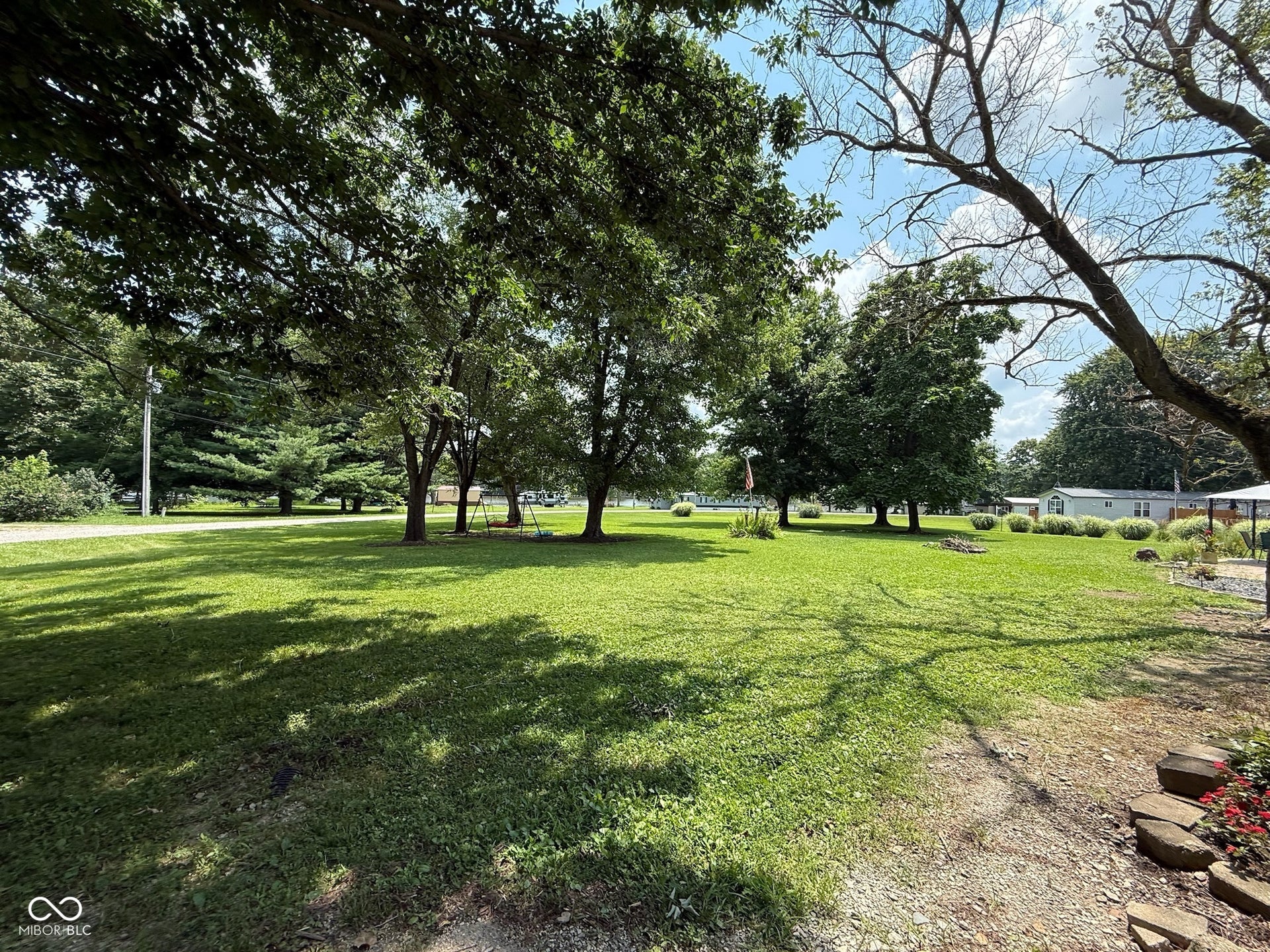 Expansive green lawn with mature trees providing dappled shade