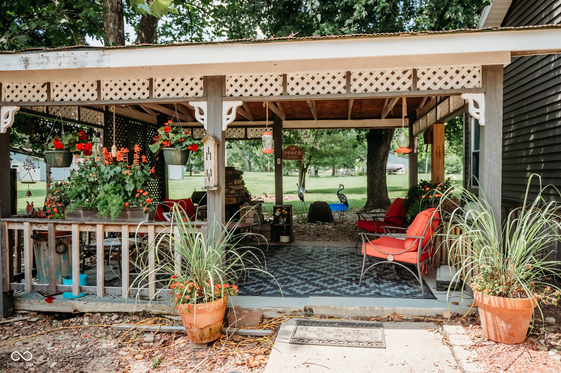 Covered patio featuring a decorative lattice border, robust wooden posts, and a patterned outdoor rug