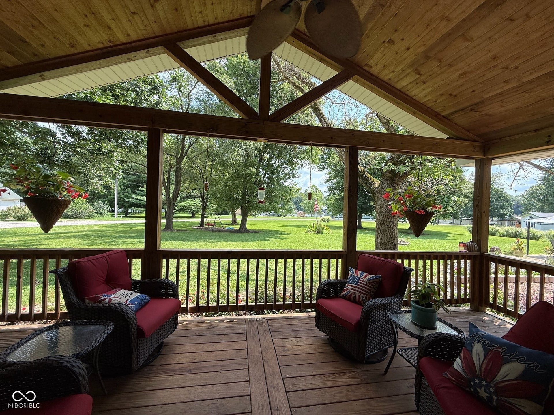 Spacious covered porch with a natural wood-finish ceiling, exposed beams, and a ceiling fan