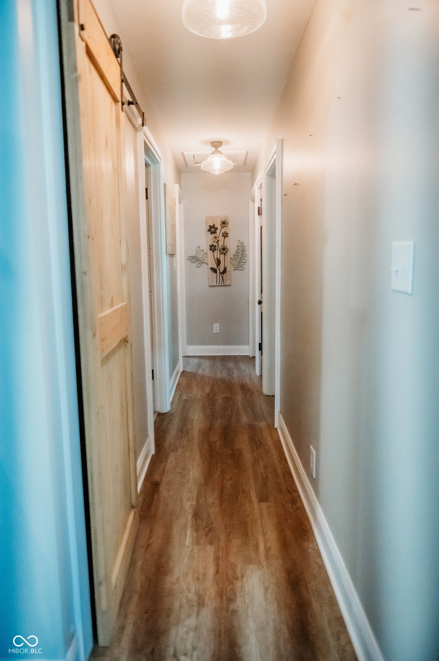 Hallway featuring wood-finish flooring and light gray wall paint