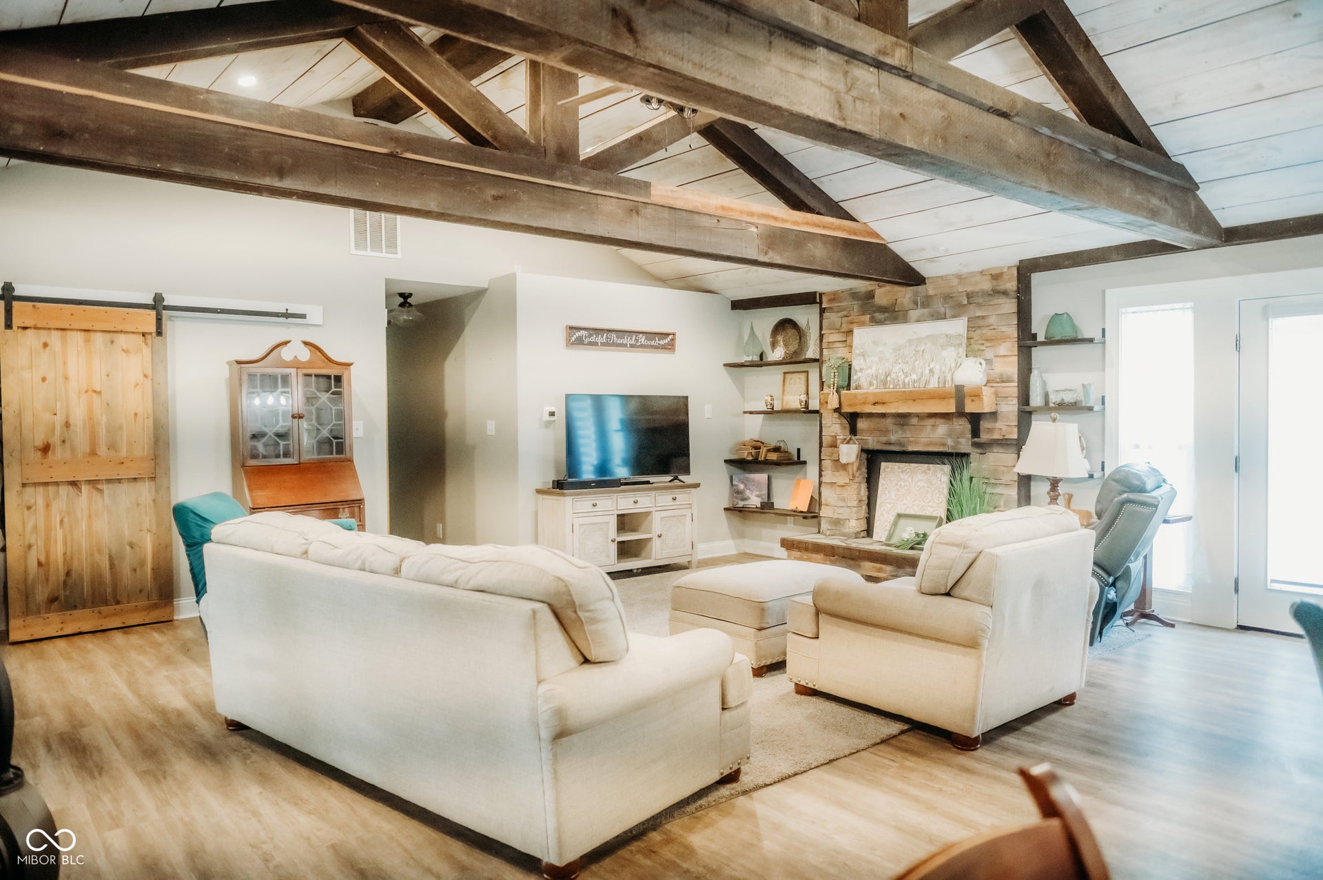 Spacious living area featuring a vaulted ceiling with exposed wood beams and wood-finish paneling