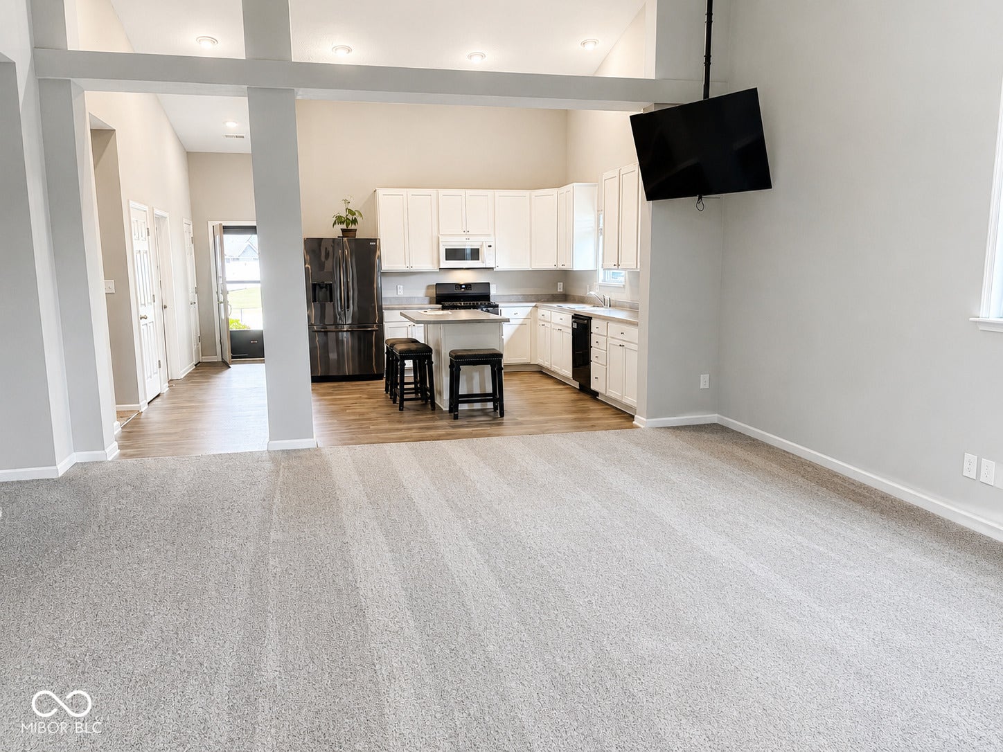 Open-concept interior with vaulted ceilings, recessed lighting, wood-finish flooring, and light-colored carpeting