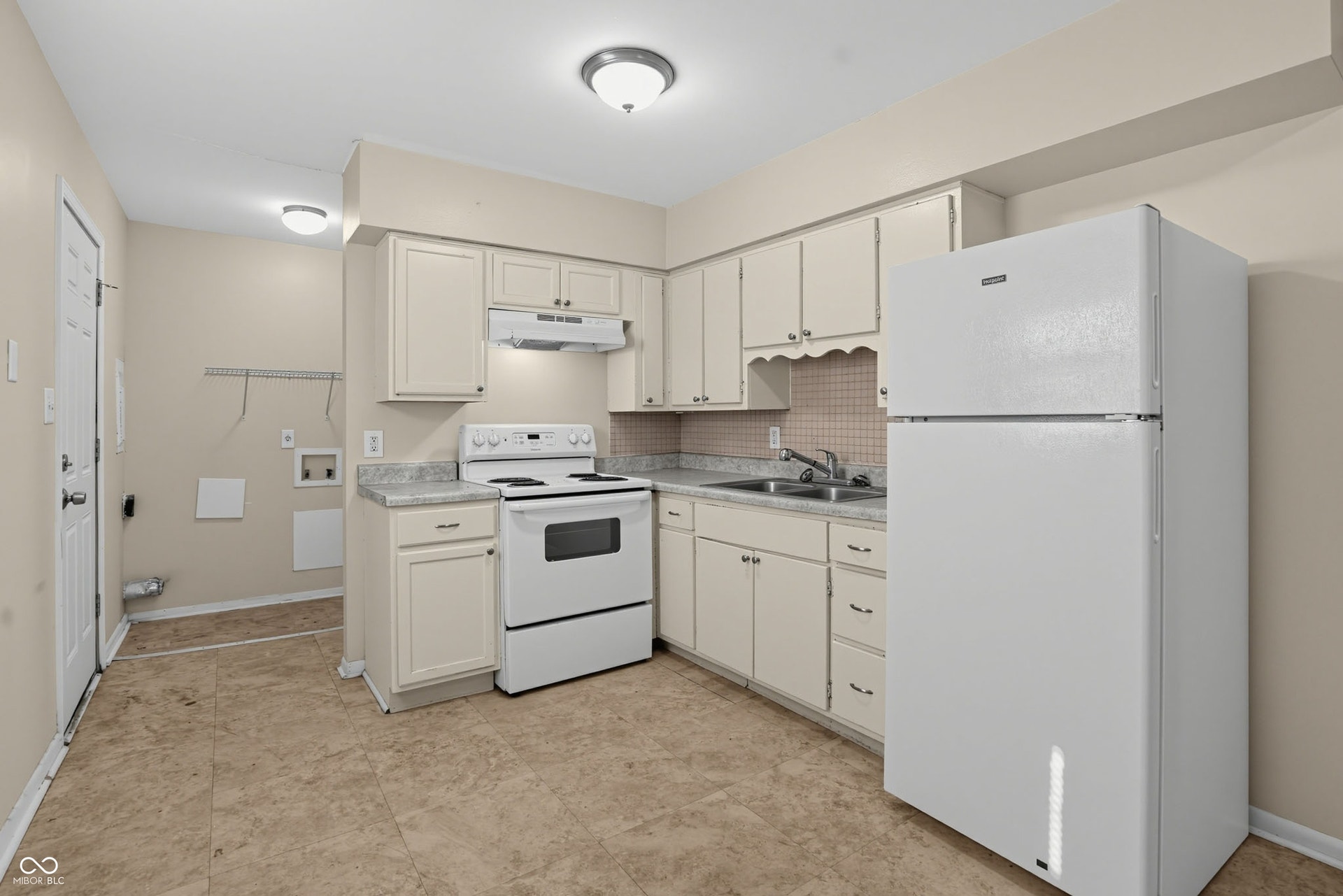 Kitchen featuring white cabinetry, white appliances, a tile backsplash, and a double basin sink