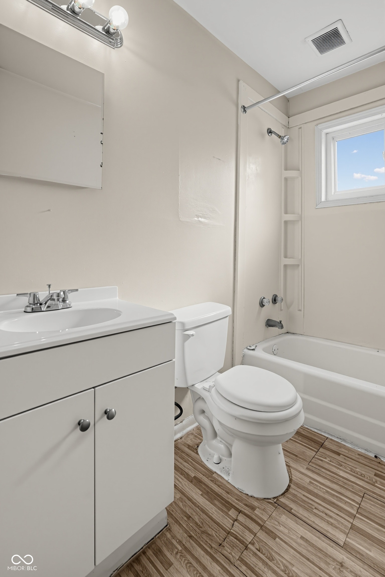 Bathroom featuring a vanity with integrated sink, toilet, and a combined shower and bathtub