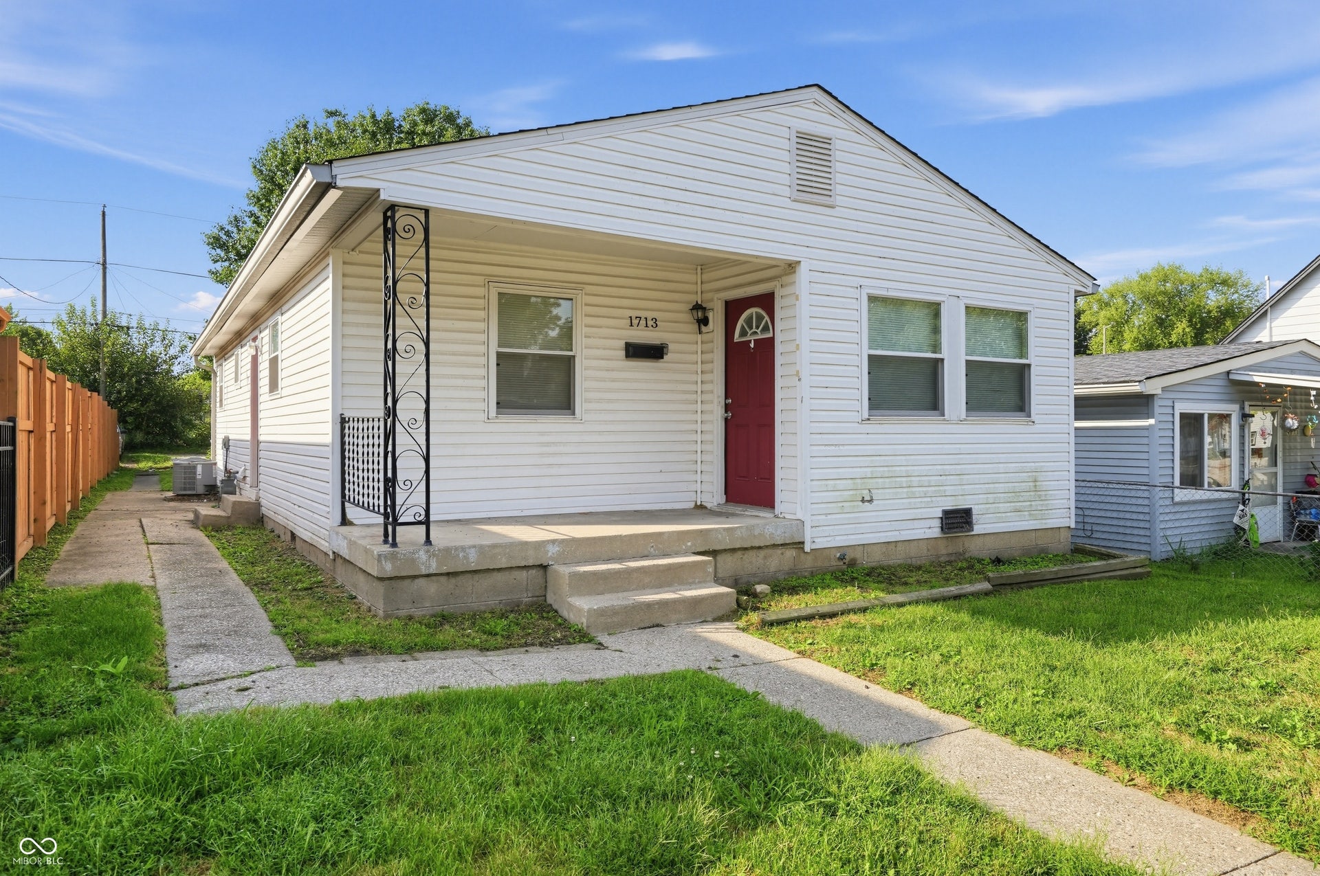 White siding exterior with a red entry door, covered porch, and concrete front steps