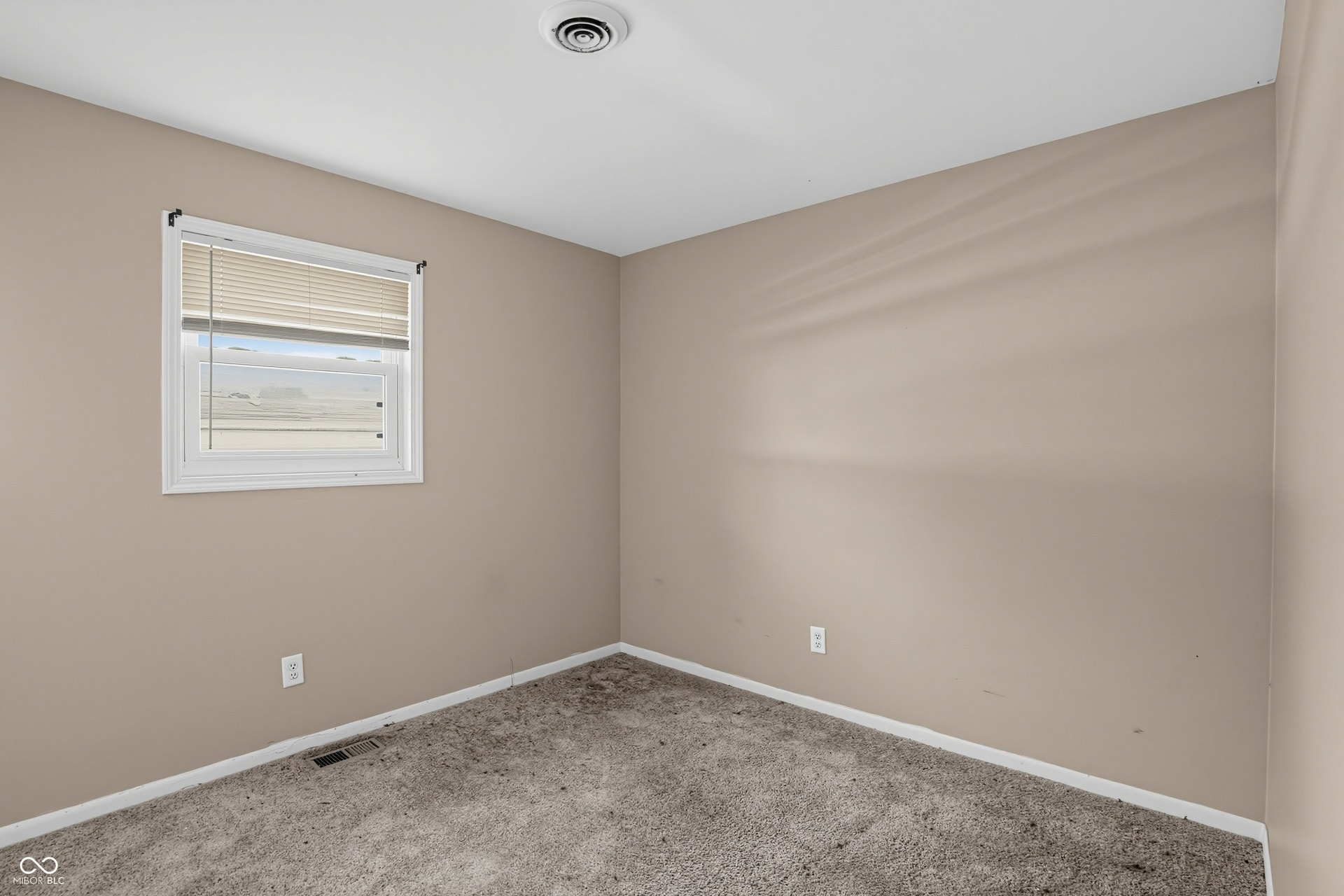 Recessed ceiling light, neutral-toned walls, and window with blinds