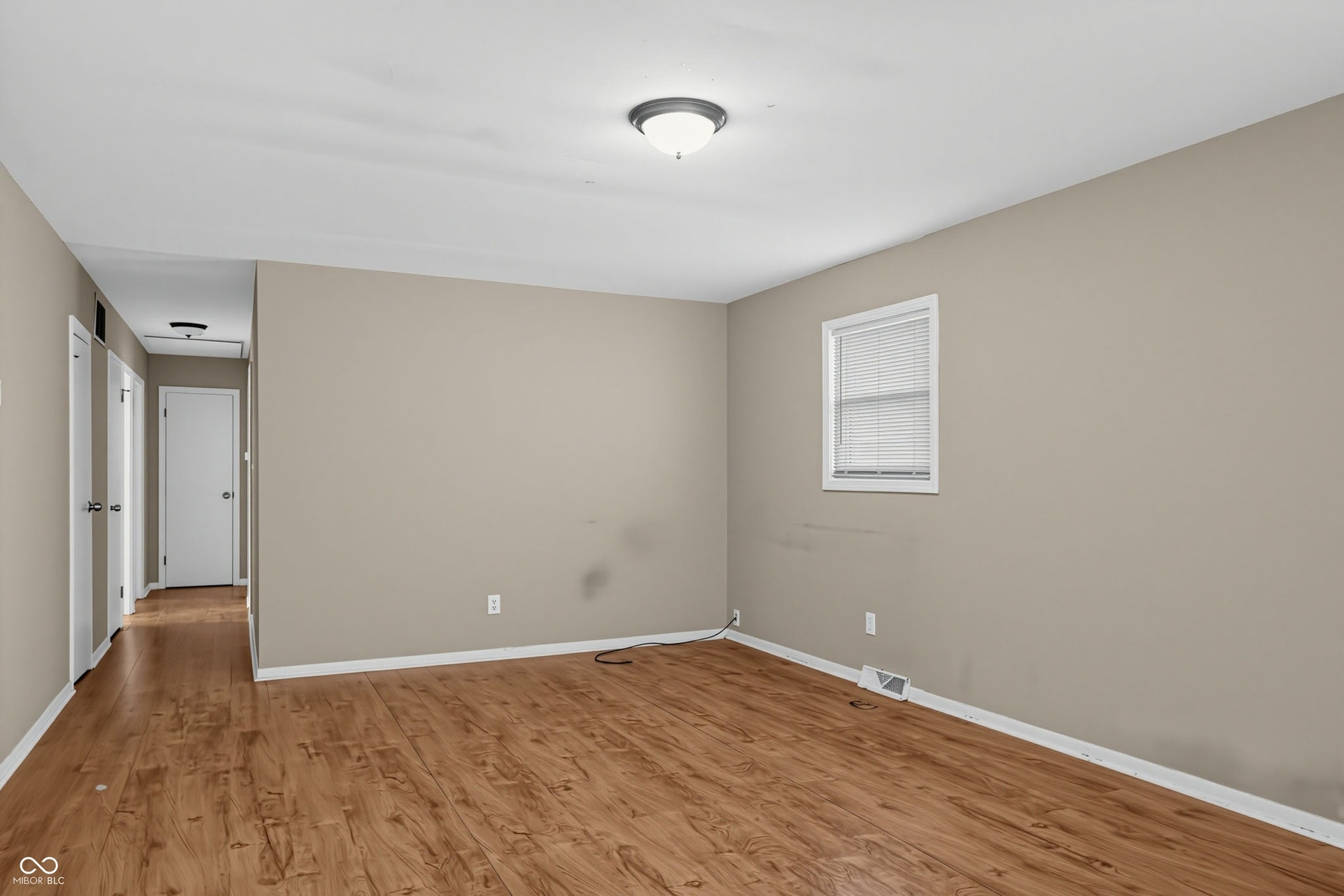 Wood-finish flooring, neutral wall tones, white trim, and a ceiling-mounted light fixture