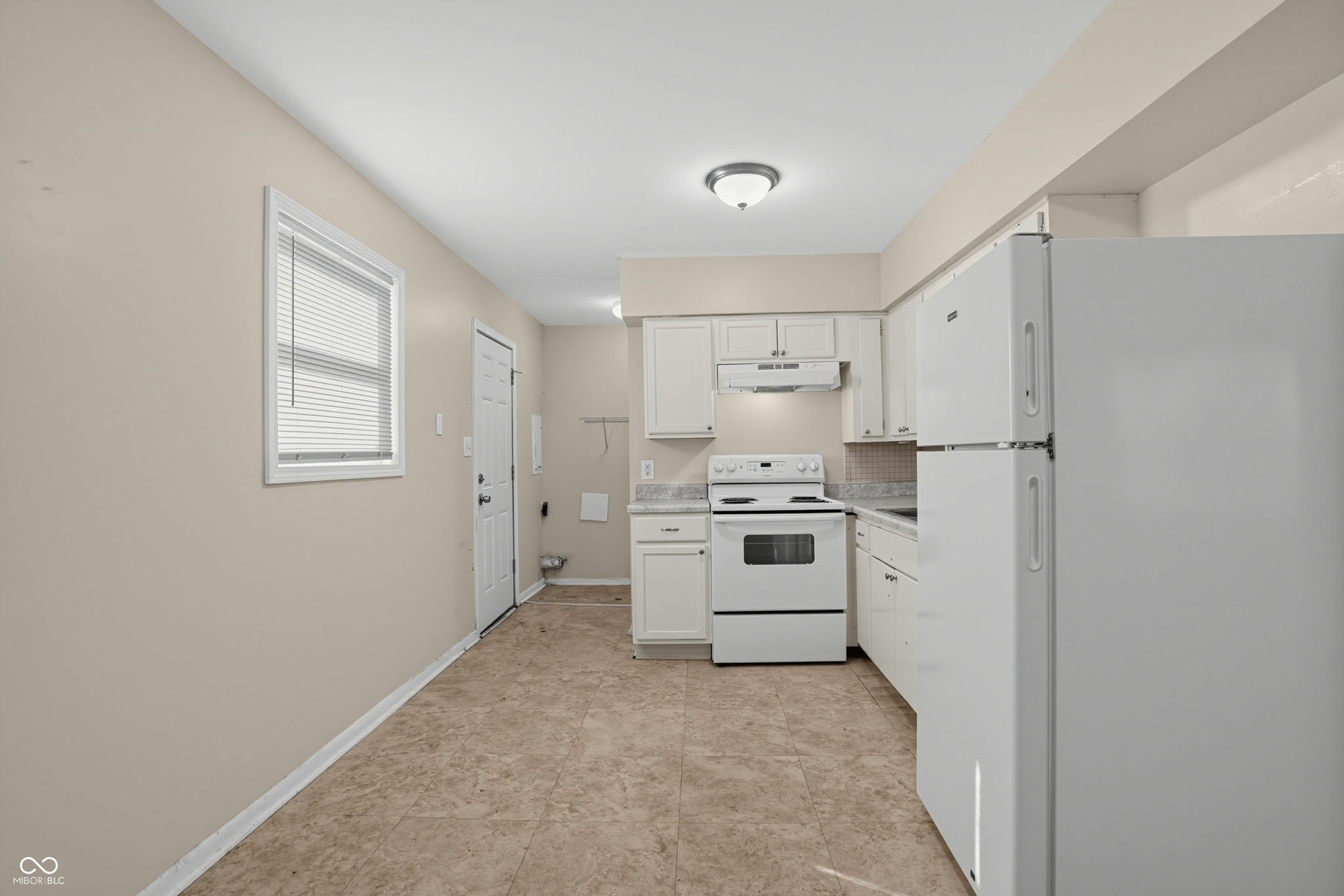 Kitchen featuring white cabinetry, light-toned countertops, white appliances, and resilient flooring