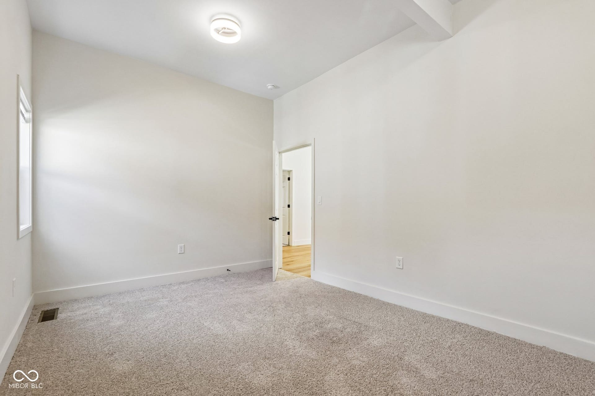Sloped ceiling with recessed lighting, light gray carpeting, white walls, and a window with white trim